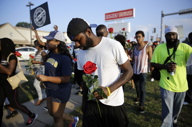 Protesters move down the street, many carrying roses, Aug. 18, 2014, in Ferguson, Mo. (AP/Jeff Roberson)