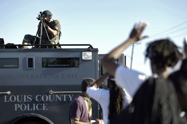 A member of the St. Louis County Police Department points his weapon in the direction of a group of protesters in Ferguson, Mo., Aug. 13, 2014. (AP/Jeff Roberson)