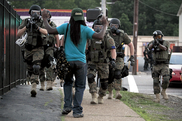 Police wearing riot gear walk toward a man with his hands raised Monday, Aug. 11, 2014, in Ferguson, Mo. (AP/Jeff Roberson)