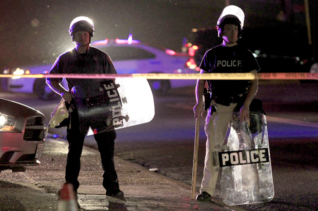 Police wearing riot gear stand at a post as they wait for a crowd to disperse Monday, Aug. 11, 2014, in Ferguson, Mo. (AP/Jeff Roberson)