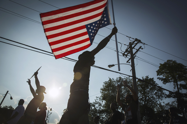 Demonstrators march down West Florissant with a U.S. flag during a peaceful march in Ferguson, Missouri August 18, 2014. (Reuters/Lucas Jackson)