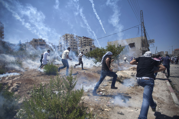 Palestinians run for cover during clashes with Israeli soldiers following a protest against the war in the Gaza Strip, outside Ofer, an Israeli military prison near the West Bank city of Ramallah, Aug. 1, 2014. (AP/Majdi Mohammed)