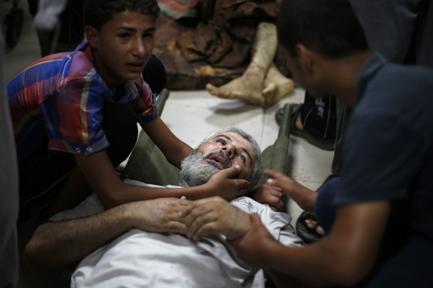 A Palestinian boy comforts his father, who medics said was wounded by Israeli shelling in Shejaia, at a hospital in Gaza City, July 30, 2014. (Reuters/Suhaib Salem)