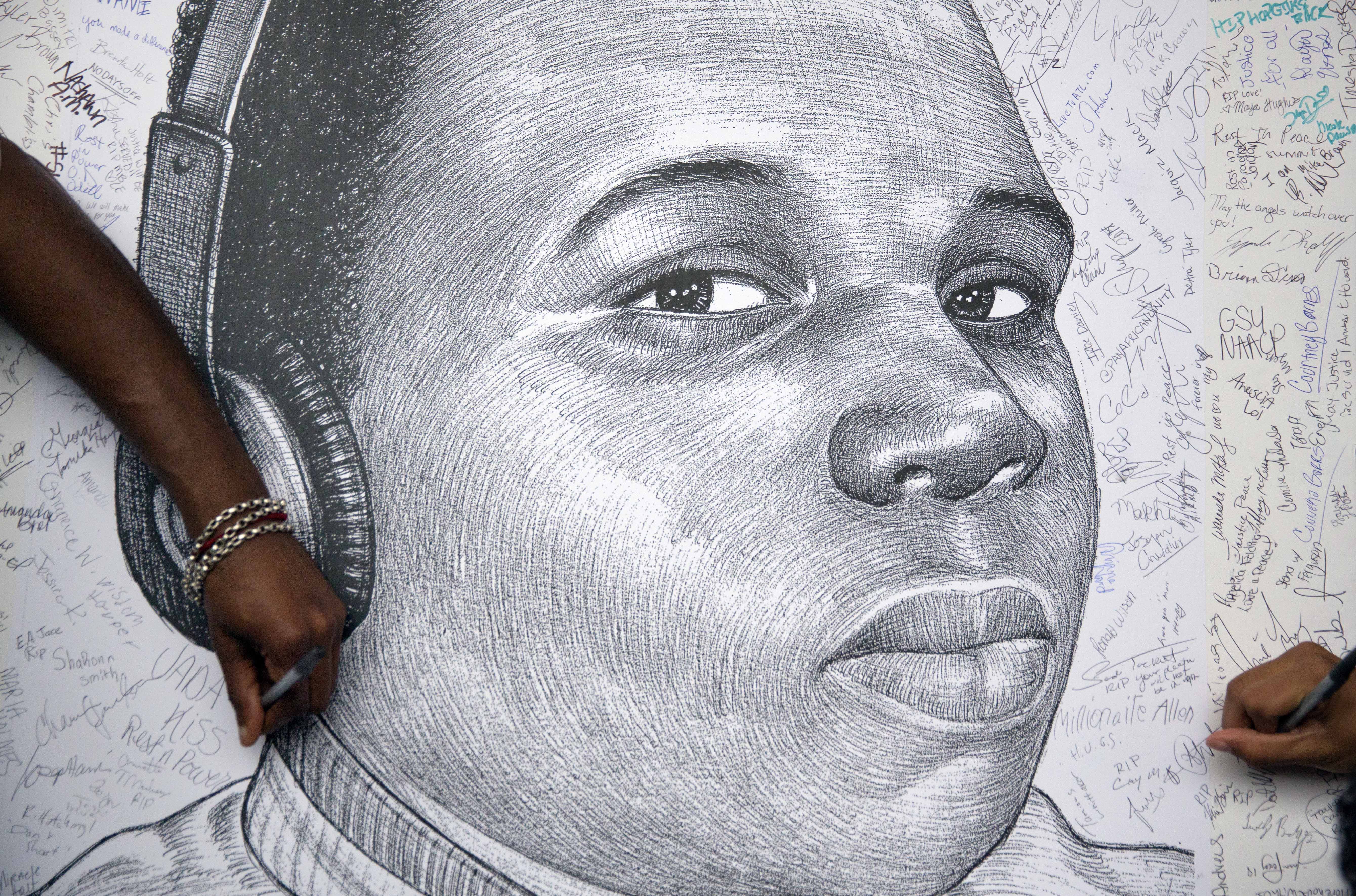 In a Monday, Aug. 18, 2014 file photo, protestors autograph a sketch of Michael Brown during a protest, in Atlanta. Michael Brown Jr. was on the verge of starting college, eager to launch himself into the adult world. Instead, on Monday hell be mourned at his funeral, more than two weeks after his fatal shooting by a white police officer. (AP/David Goldman)