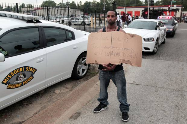 Louis Head, stepfather to 18-year-old Michael Brown who was fatally shot by police, holds a sign in Ferguson, Mo., near St. Louis on Saturday, Aug. 9, 2014 (AP Photo/St. Louis Post-Dispatch, Huy Mach)