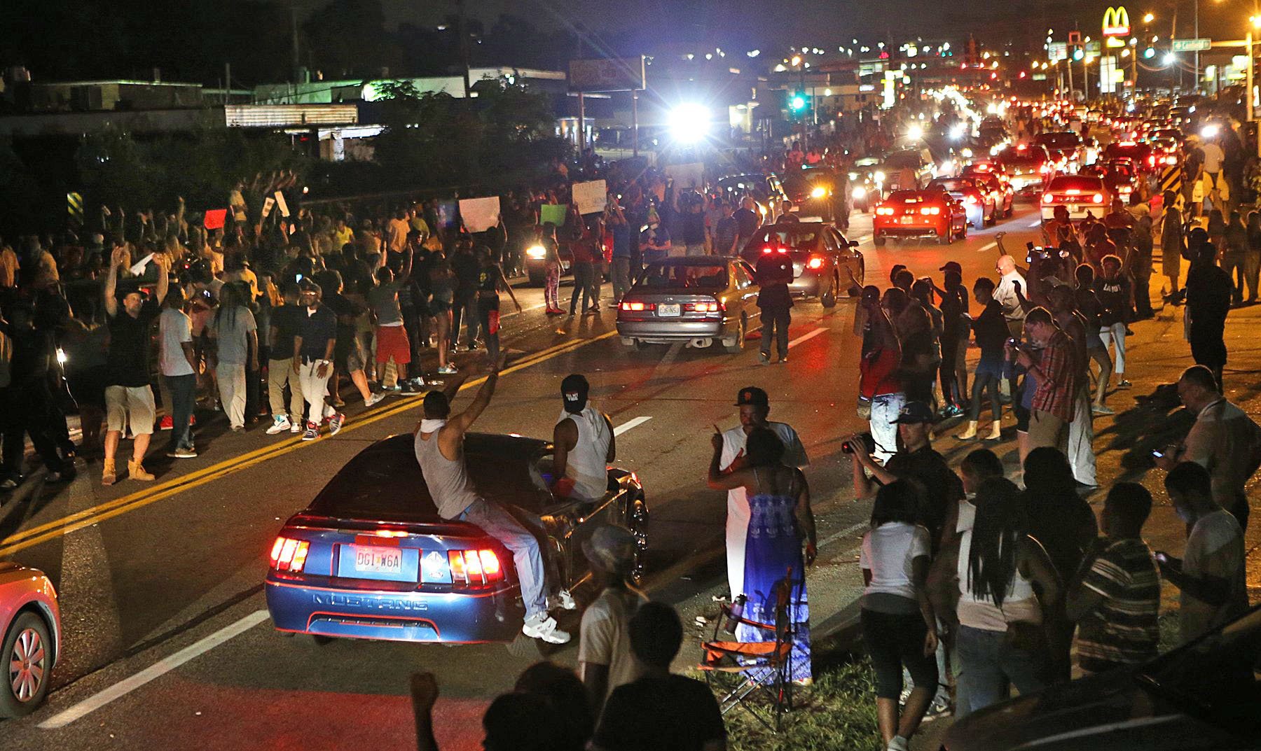 Many people drove down the street honking their horns, raising their arms, and holding signs on W. Florissant in Ferguson on Thursday evening, Aug. 14, 2014, as some demonstrators stood in the middle of the street. (AP Photo/St. Louis Post-Dispatch, J.B. Forbes))