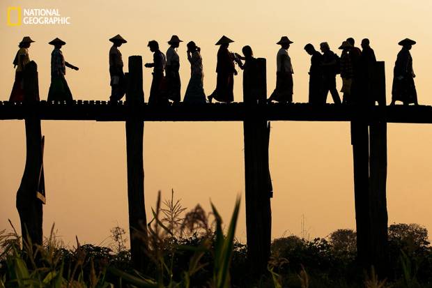 Ladies with Conical hats going to the right while locals, Monks, Kids, tourist going to the left as they were walking on the U Bien Bridge made out of teakwood at Mandalay, Myanmar (April Badilles, National Geographic 2014 Photo Contest)
