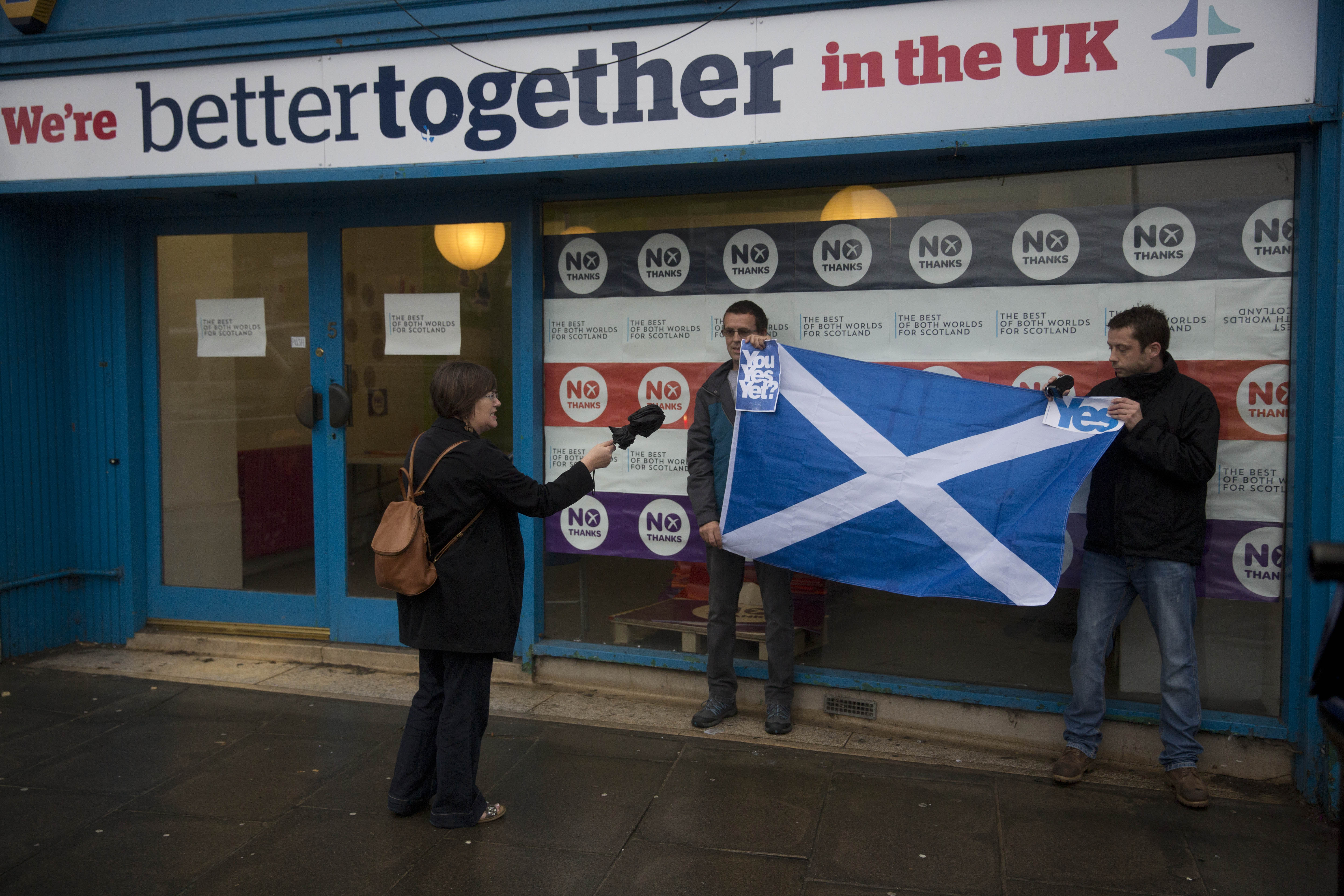 A passerby argues with two Scottish independence referendum 'Yes' supporters holding a Scottish Saltire flag outside the "Better Together" No campaign offices in Edinburgh, Scotland, Monday, Sept. 15, 2014.  If Scottish voters this week say Yes to independence, not only will they tear up the map of Great Britain, they'll shake the twin pillars of Western Europe's postwar prosperity and security  the European Union and the U.S.-led NATO defense alliance.  () (AP Photo/Matt Dunham)