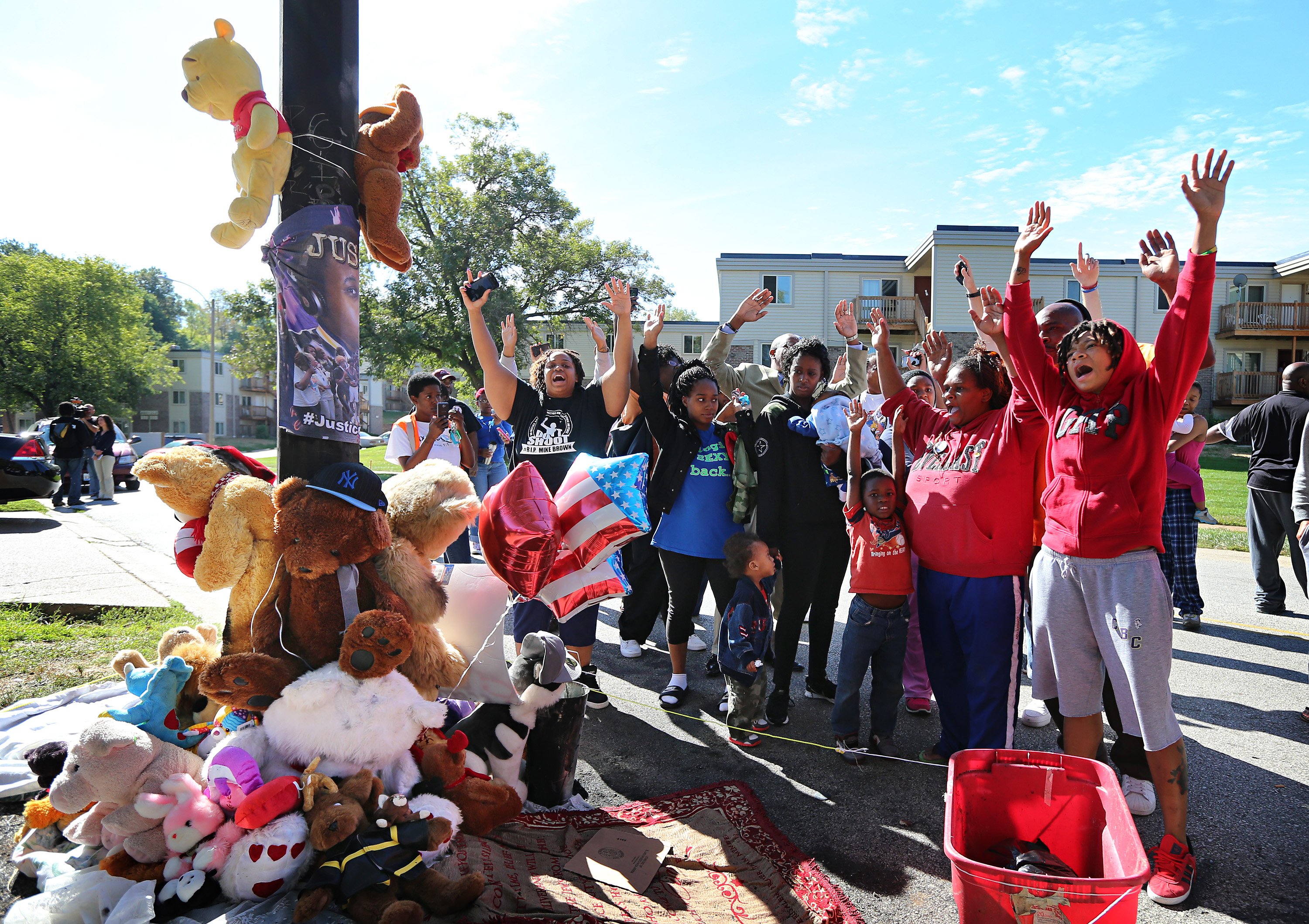 Protesters perform a "hands up, don't shoot" chant at a new teddy bear memorial on Tuesday, Sept. 23, 2014, in Ferguson, Mo., near the spot of where Michael Brown was shot by Ferguson police office Darren Wilson on Aug. 9.  The original teddy bear memorial was destroyed by fire earlier Tuesday morning. Ferguson police spokesman Devin James says the cause of the fire is under investigation. (AP/St. Louis Post-Dispatch, David Carson)