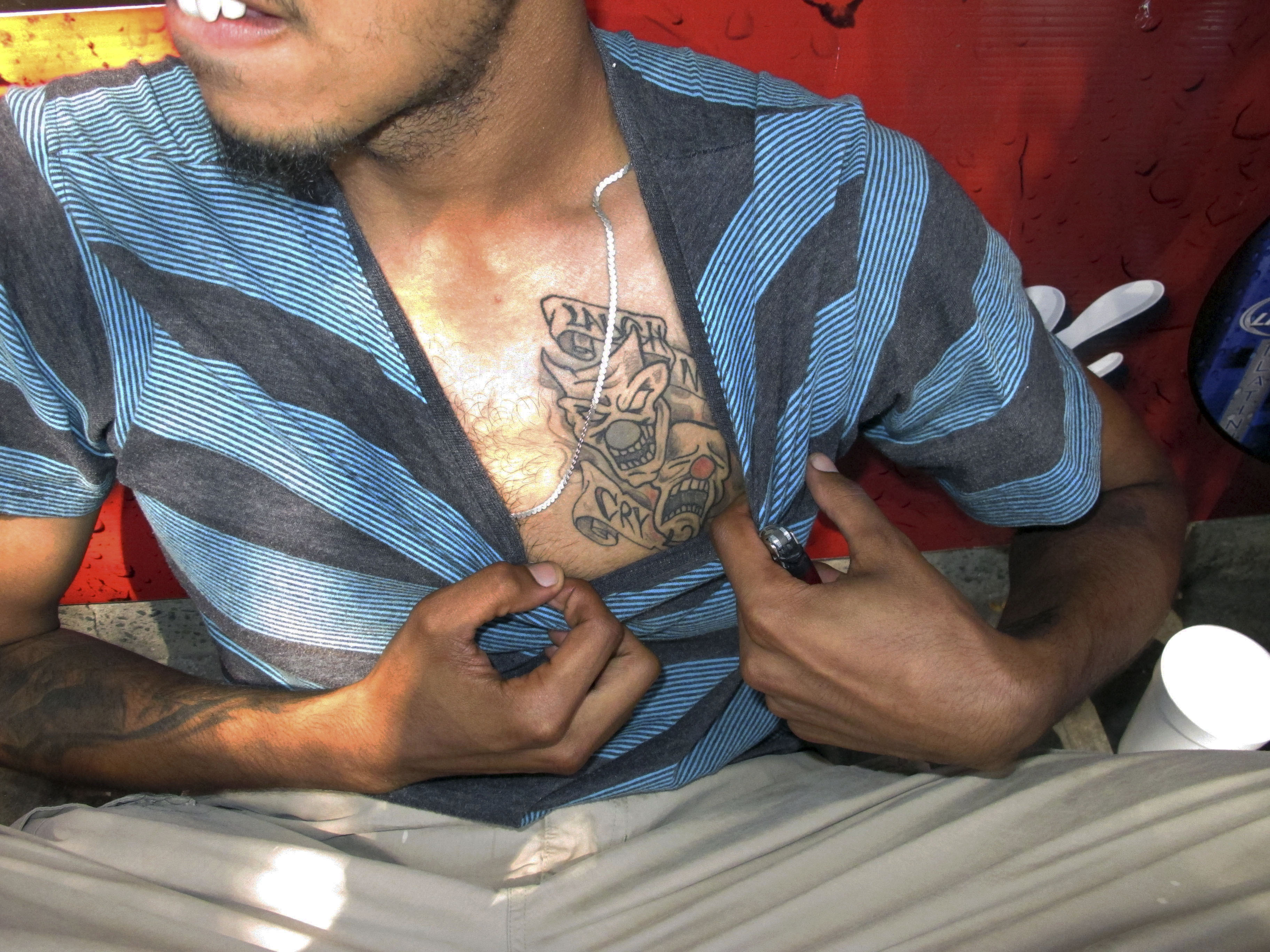 In this Sept. 5, 2014 photo, a reputed member of the Los Solidos street gang shows his tattoo to police in Hartford, Conn. ((AP Photo/Dave Collins))