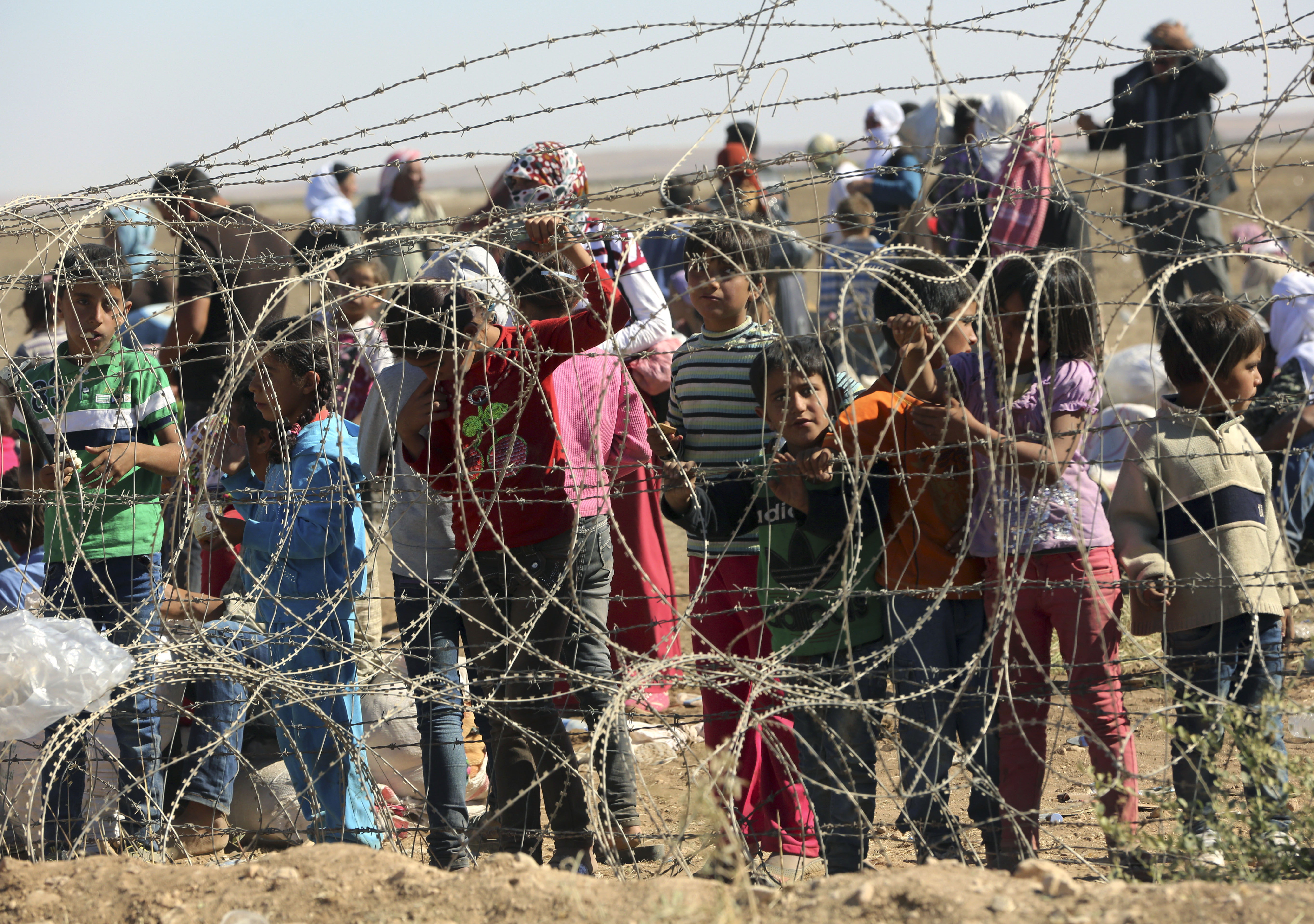 Several hundred Syrian refugees wait to cross into Turkey at the border in Suruc, Turkey, Sunday, Sept. 21, 2014. Turkey opened its border Saturday to allow in up to 60,000 people who massed on the Turkey-Syria border, fleeing the Islamic militantsâ advance on Kobani.(AP Photo/Burhan Ozbilici) (Burhan Ozbilici)