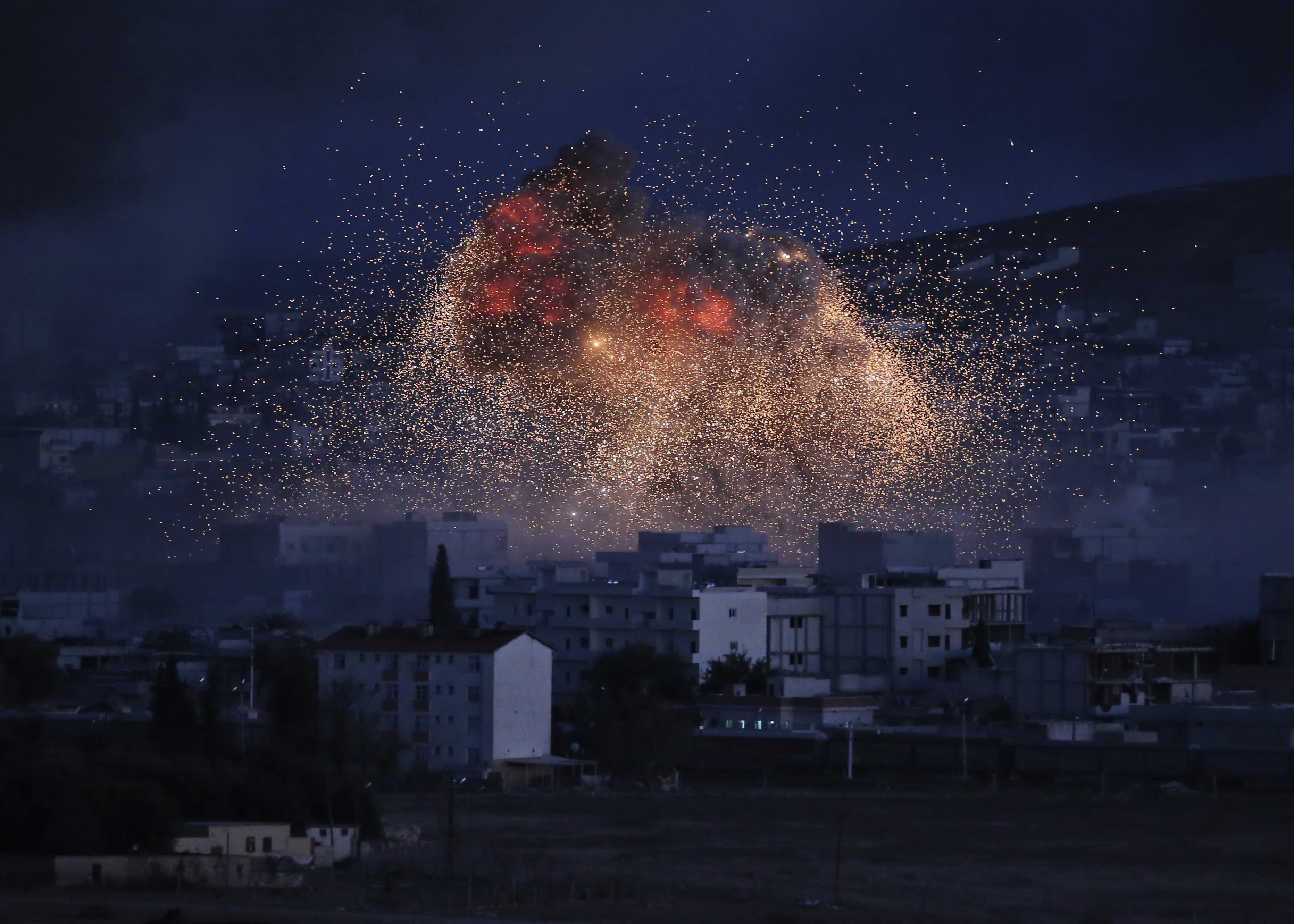 AP10ThingsToSee - Thick smoke and flames from an airstrike by the U.S.-led coalition rise in Kobani, Syria, as seen from a hilltop on the outskirts of Suruc, at the Turkey-Syria border, Monday, Oct. 20, 2014. Kobani, also known as Ayn Arab, and its surrounding areas, has been under assault by extremists of the Islamic State group since mid-September and is being defended by Kurdish fighters. (AP Photo) (AP)