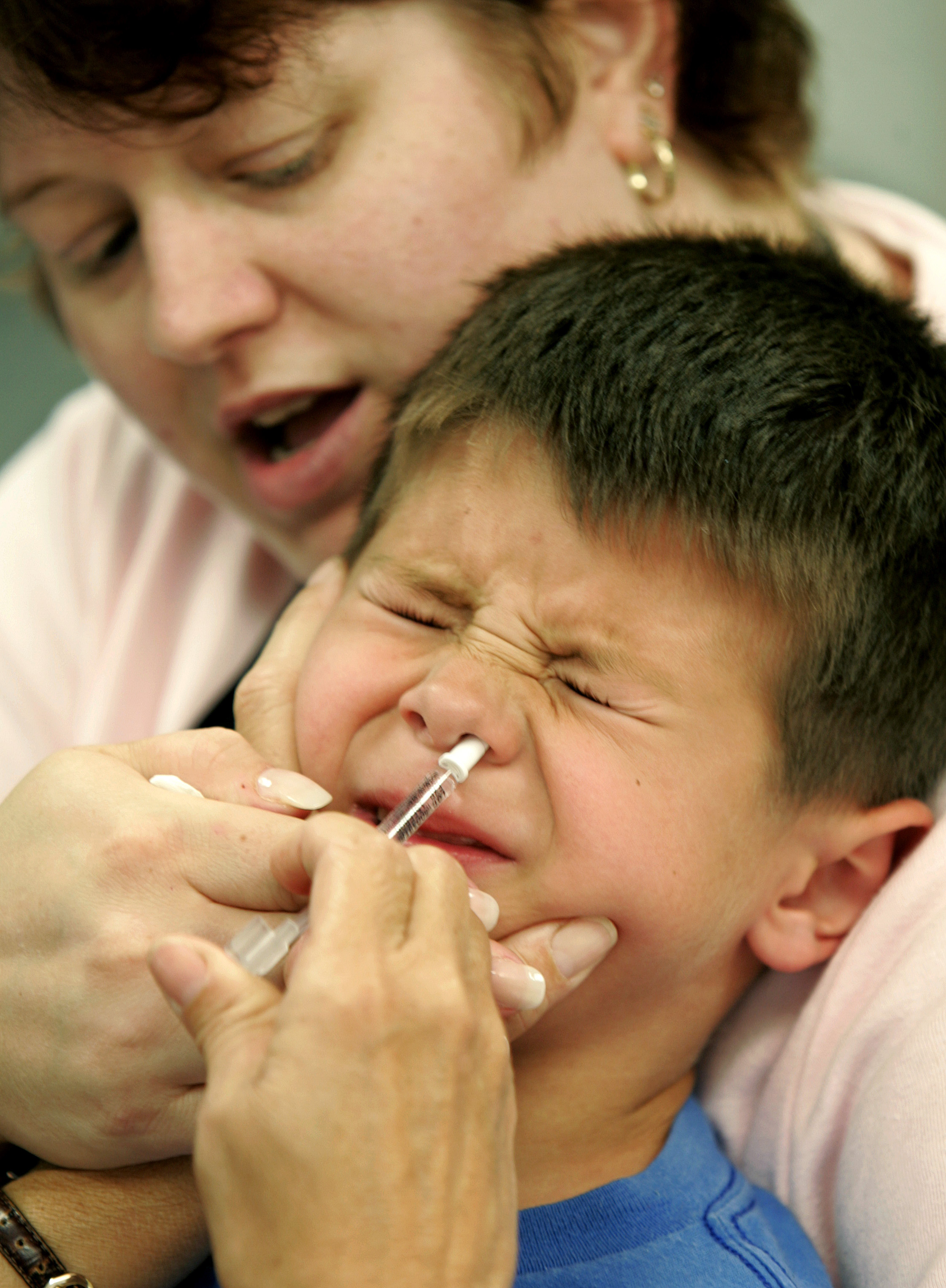 Eric Krex, 6, reacts as he is held by his mother, Margaret, while a nurse gives him a FluMist influenza vaccination (Photo/Chris Gardner)