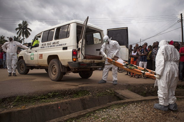 Healthcare workers load a man suspected of suffering from the Ebola virus onto an ambulance in Kenema, Sierra Leone, Sept. 24, 2014. (AP/Tanya Bindra)