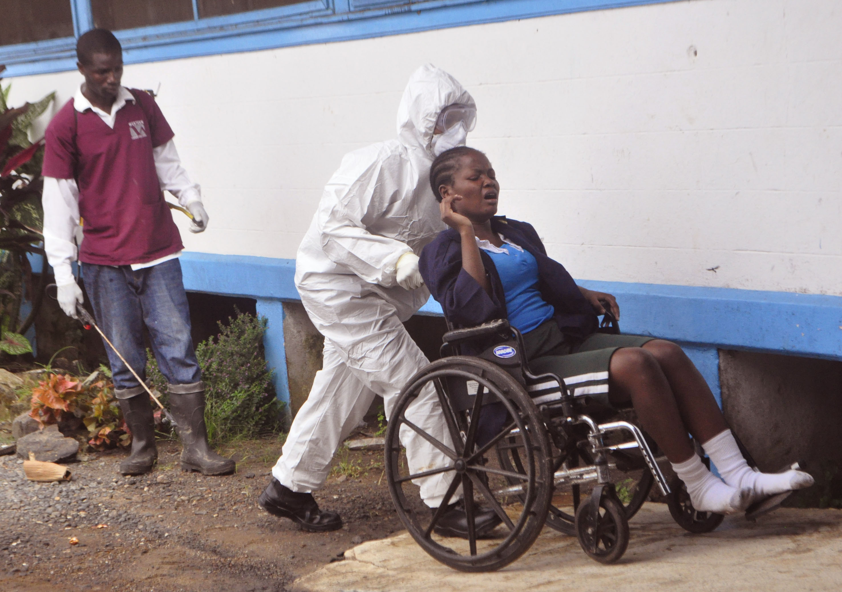 In this photo taken on Saturday, Nov. 1, 2014,  a woman prisoner suspected of suffering from the Ebola virus, from Tubmanburg central prison, is pushed in a wheelchair towards a medical vehicle,  to be taken to an Ebola treatment center in Monrovia, Liberia. The Ebola outbreak has spawned a silent killer, experts say: hidden cases of malaria, pneumonia, typhoid and the like that are going untreated because people in the countries hardest hit by Ebola either cannot find an open clinic or are too afraid to go to one. (AP Photo/ Abbas Dulleh) (AP)