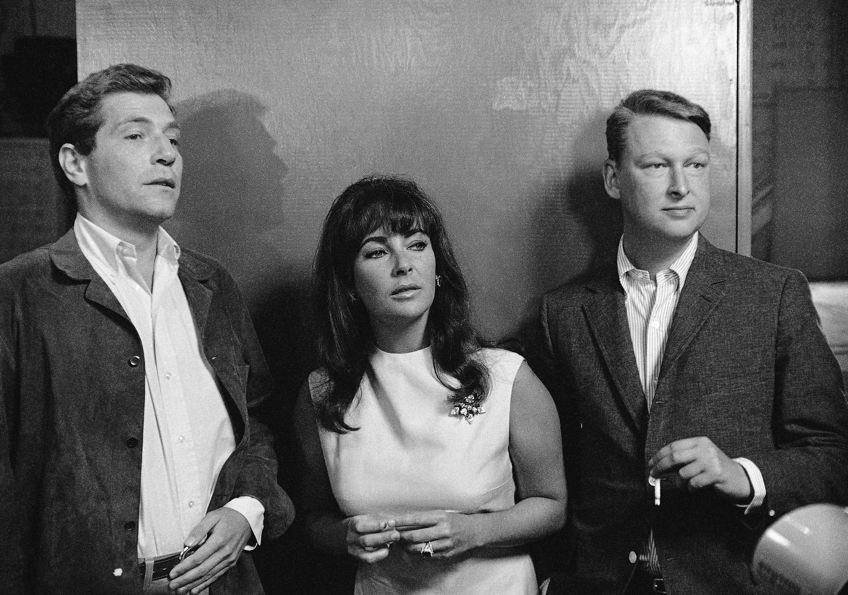 FILE - Elizabeth Taylor is flanked by actor George Segal, left, a co-star in Whos Afraid of Virginia Woolf? and Mike Nichols director of the film, as they watched preparation in this Oct. 20, 1965 file photo taken in Hollywood, ABC News confirms Nichols died Wednesday Nov. 19, 2014. He was 83. (AP Photo/File) (AP)