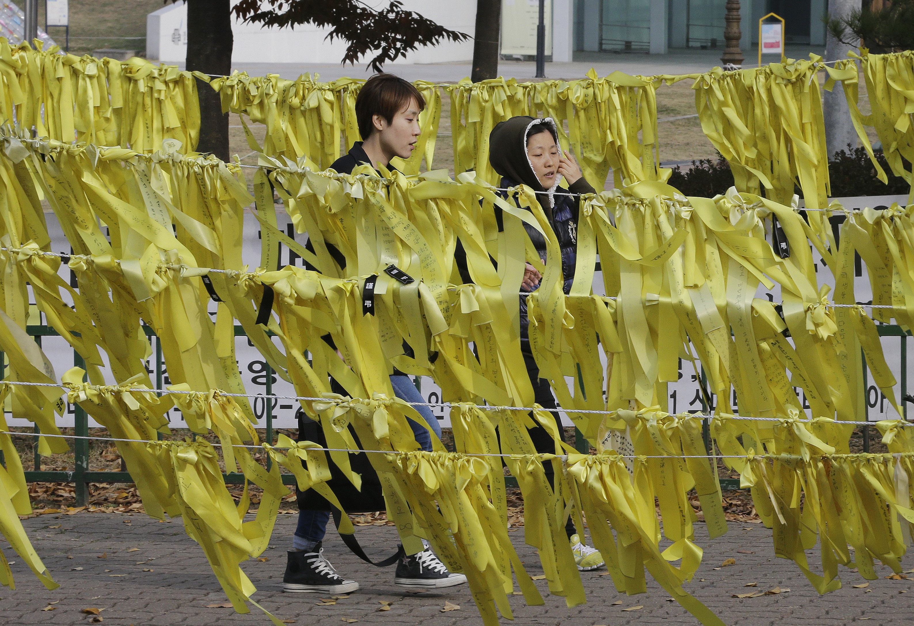 People pass by yellow ribbons with messages for missing passengers and victims aboard sunken ferry Sewol near a group memorial altar in Ansan, South Korea, Tuesday, Nov. 11, 2014. The captain of a ferry that sank earlier this year, leaving more than 300 people dead and shocking South Korea, was given a 36-year prison sentence Tuesday for negligence and abandoning his passengers.(AP Photo/Ahn Young-joon) (AP)