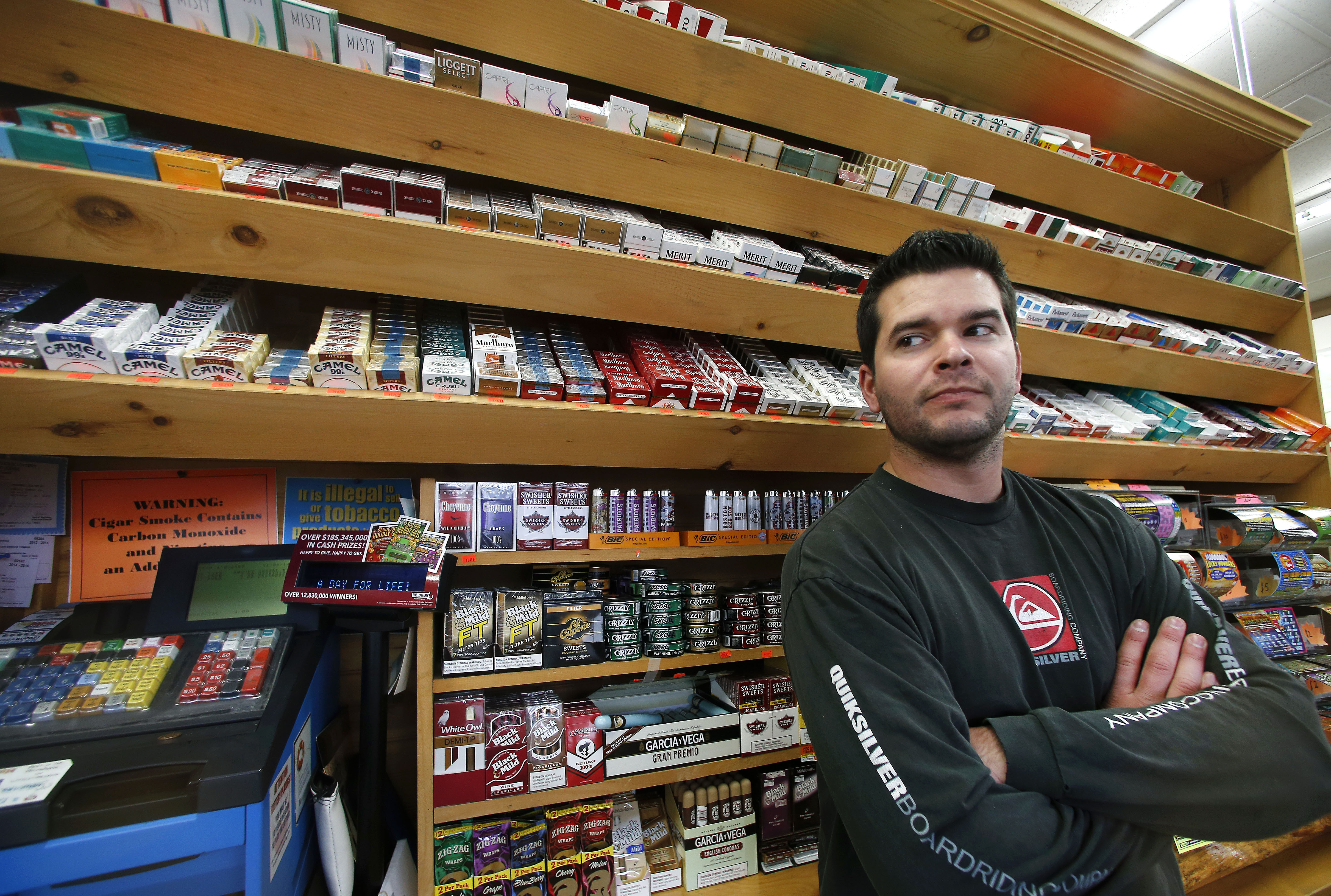 Brian Vincent poses in front of a large display of tobacco products at Vincent's Country Store in Westminster, Mass., Thursday, Nov. 6, 2014. Local officials are contemplating what could be a first: a blanket ban on all forms of tobacco and e-cigarettes, leaving some shop owners fuming. (AP Photo/Elise Amendola) (AP/Elise Amendola)