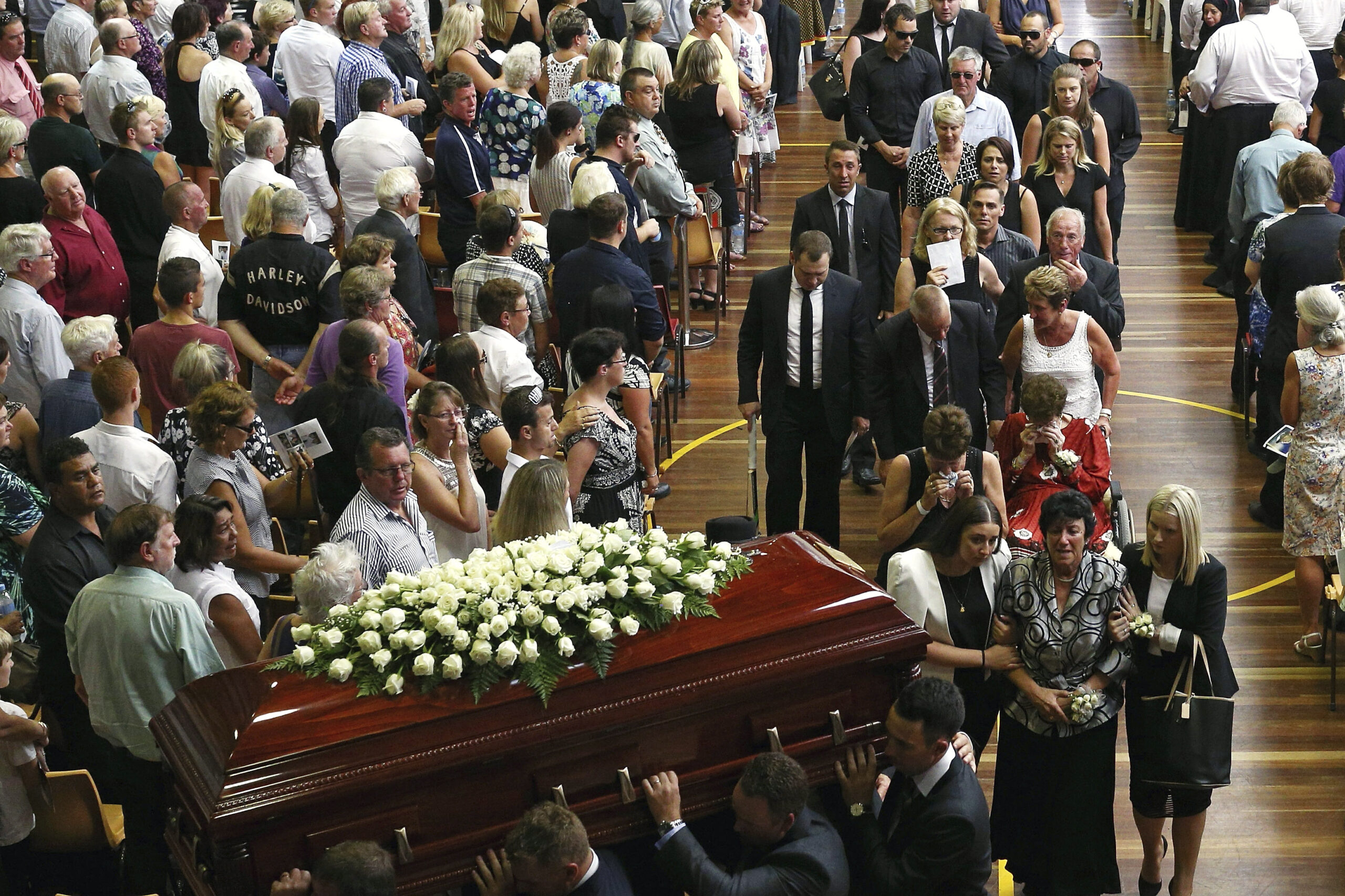 The coffin of Phillip Hughes is carried down the aisle as his mother, Virginia Hughes, second right at bottom, is comforted during his funeral in Macksville, Australia, Wednesday, Dec. 3, 2014. Hughes died last Thursday, two days after he was hit in the head during a domestic cricket match. (AP Photo/Cameron Spencer, Pool) (Cameron Spencer)