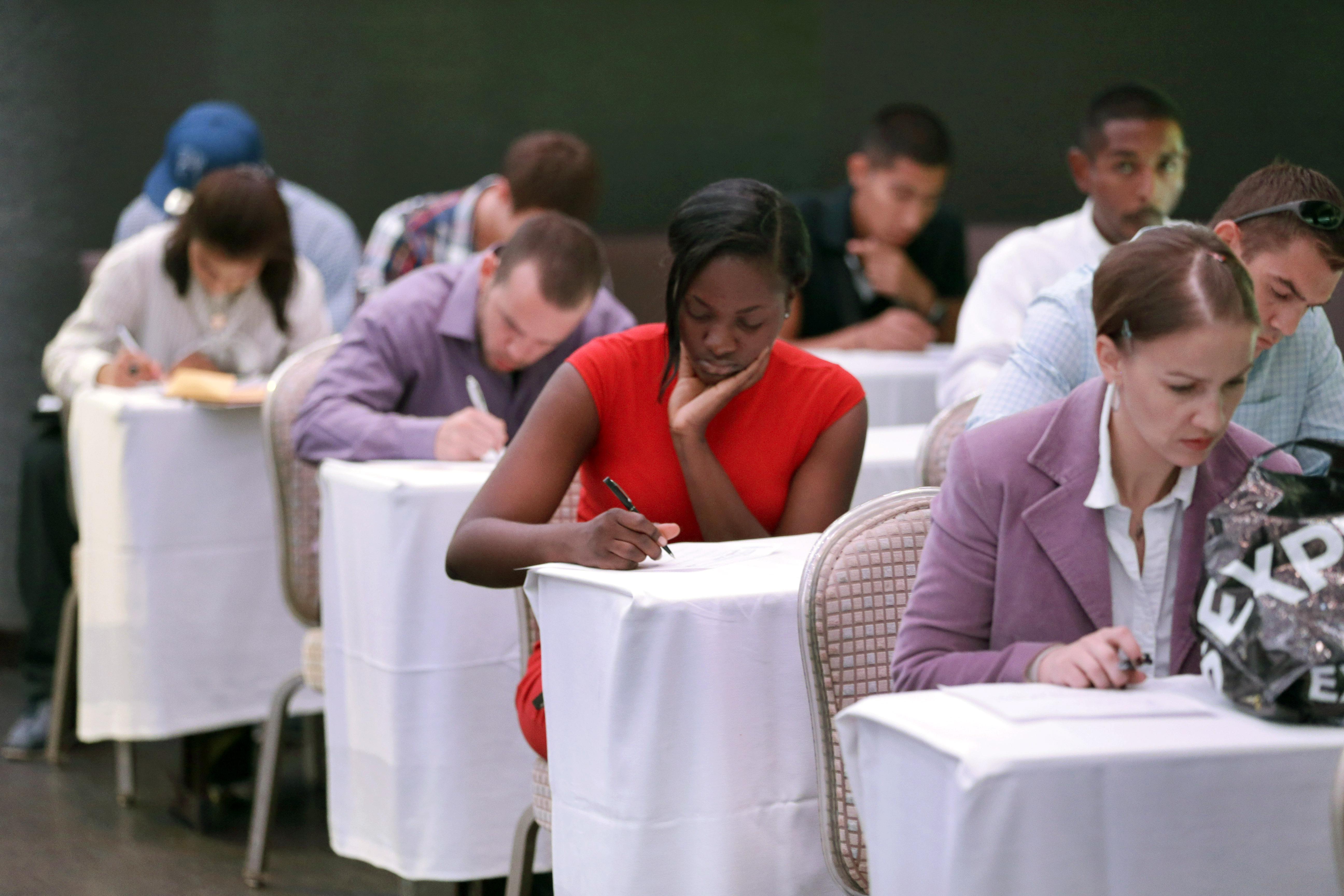 In this Monday, Oct. 6, 2014 photo, job seekers fill out forms before being interviewed during a job fair at Fontainebleau Miami Beach in Miami Beach, Fla. (AP/Wilfredo Lee)