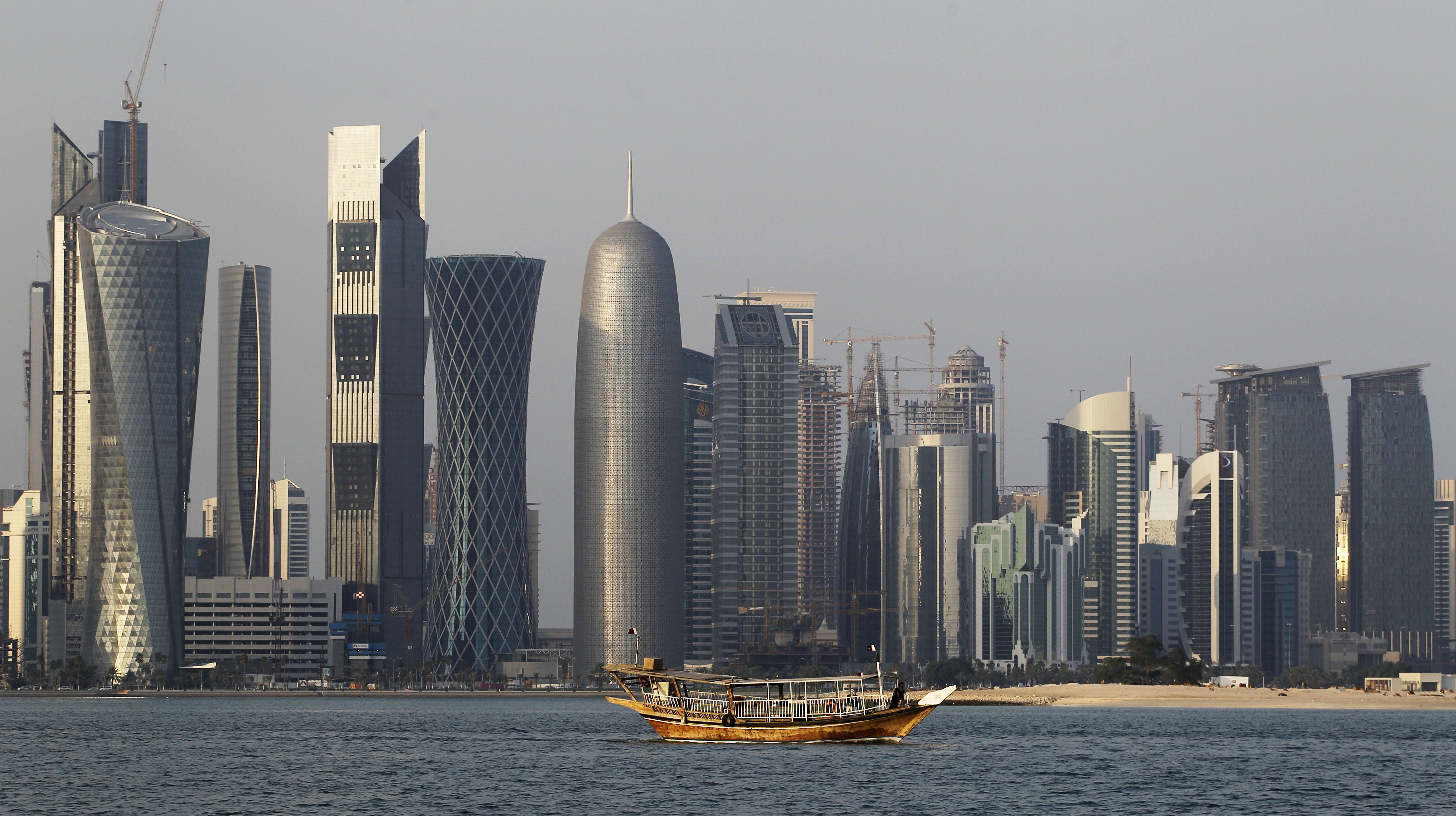 FILE - In this Thursday Jan. 6, 2011 file photo, a traditional dhow floats in the Corniche Bay area with tall buildings of the financial district in the background. The 2022 World Cup in Qatar, the wealthy oil- and gas-producing Gulf nation with giant look-at-me ambitions that belie its small size, is shaping up as a unique experience. (AP Photo/Saurabh Das, File) (AP Photo/Saurabh Das, File)