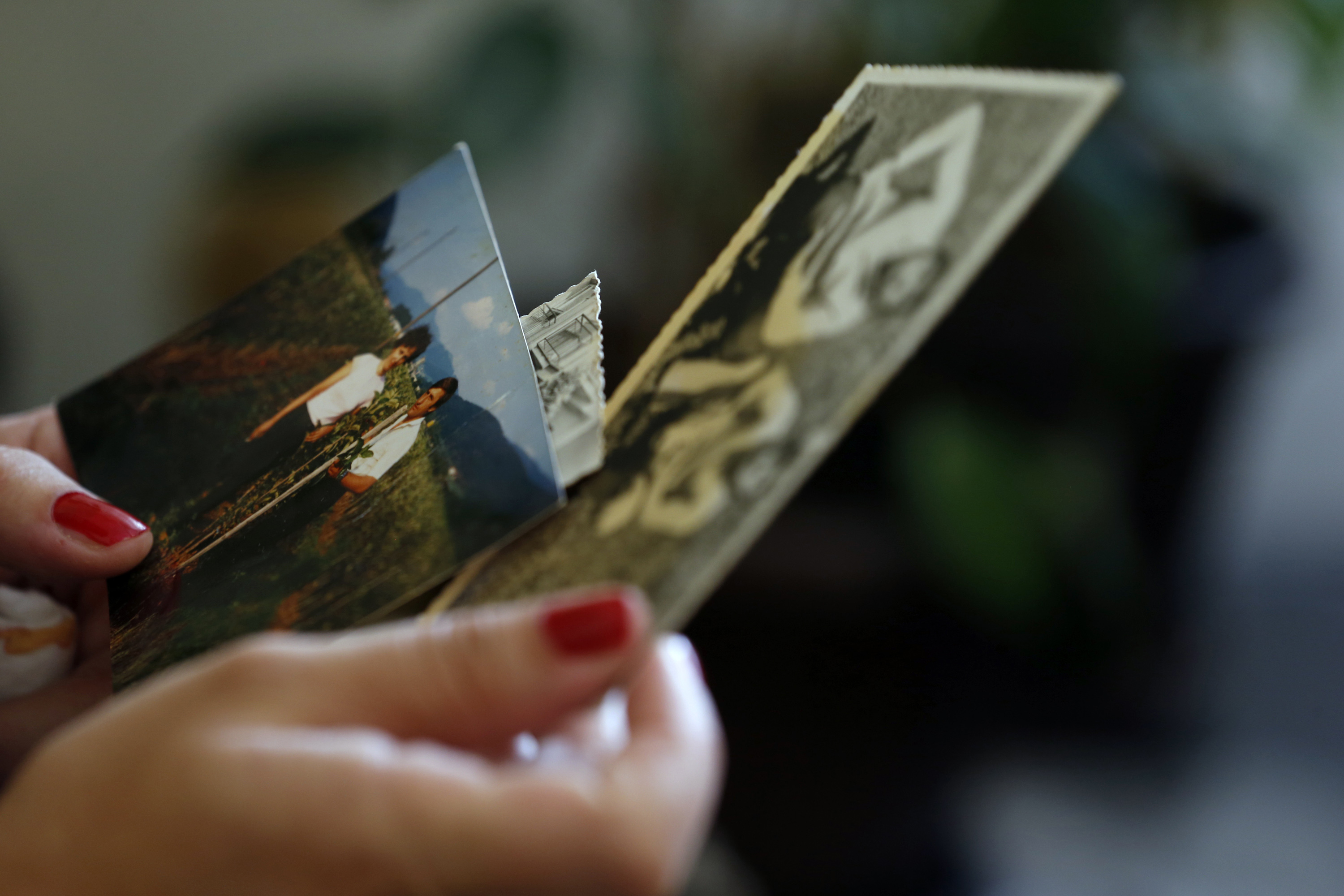 In this photo taken Wednesday, July 16, 2014, Selma Colovic-Memovic, the daughter of Fikret Memovic, looks at photographs of her father, railway worker from southwest Serbia, who was traveling back home from the capital, Belgrade, when his train unexpectedly stopped at a remote station in war-ravaged eastern Bosnia _ a lone post on the hilly boundary with Serbia, where he himself had worked only days before, in Prijepolje, Serbia. A group of armed Bosnian Serb militia _ some wearing long beards of the nationalist World War II Chetnik movement _ stormed in and checked the passengersâ IDs. They abducted only non-Serbs _ 18 Muslims and one Croat _ after recognizing their Muslim names. No one tried to stop them. The train went on in eery silence among remaining passengers after some 30 minutes. (AP Photo/Darko Vojinovic) (Darko Vojinovic)