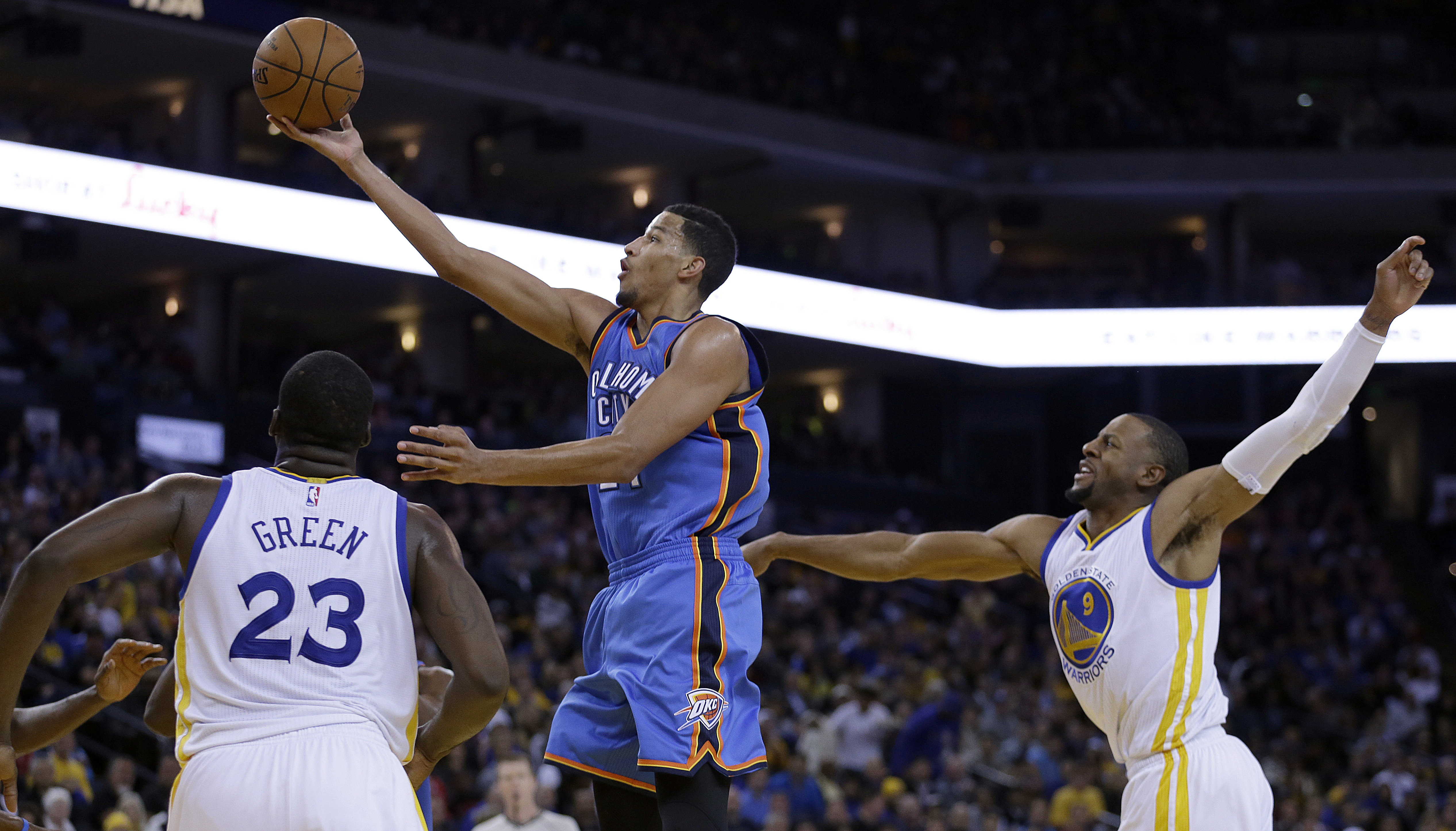 Oklahoma City Thunder guard Andre Roberson lays up a shot between Golden State Warriors' Draymond Green (23) and Andre Iguodala during the second half of an NBA basketball game Thursday, Dec. 18, 2014, in Oakland, Calif. The Warriors won 114-109. (AP Photo/Ben Margot) (AP)