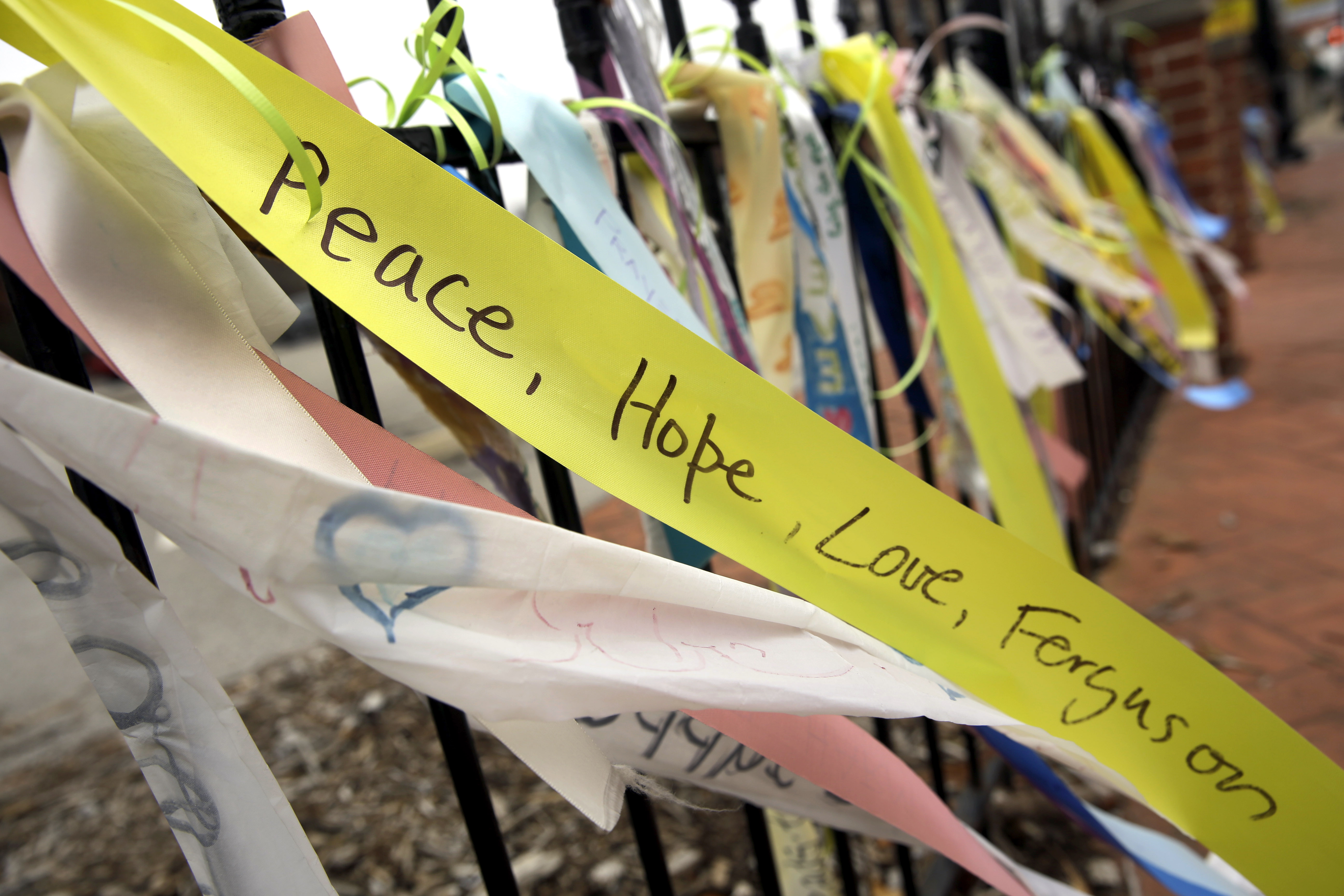 In this Dec. 9, 2014, photo, brightly colored ribbons flutter from a wrought-iron fence along the a main thoroughfare in Ferguson, Mo. Up and down South Florissant Road, paint has transformed the sheets of plywood covering windows broken during last month's rioting into works of art.  (AP Photo/Jeff Roberson) (AP)