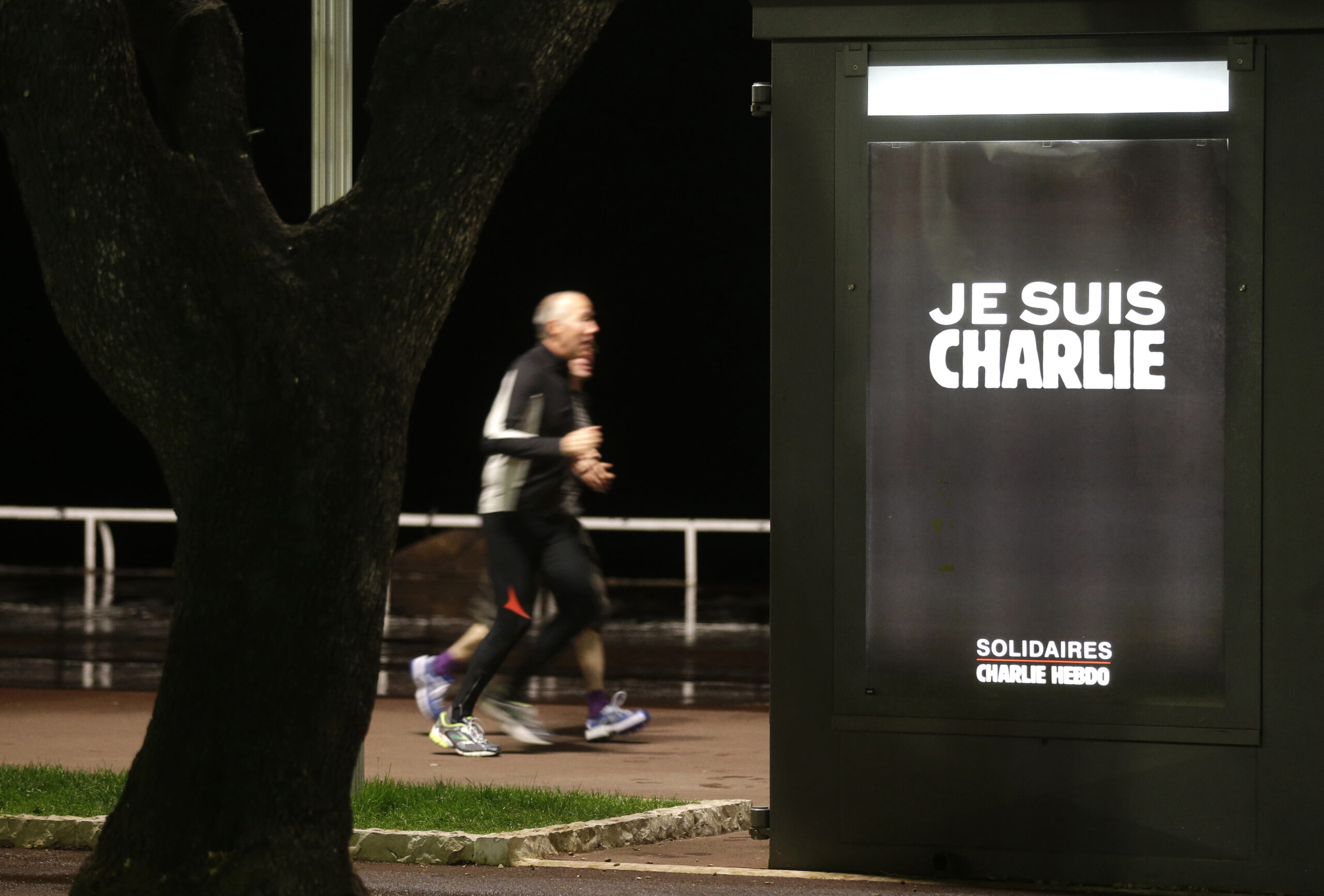 Mens runs next to a kiosk with a poster reading "I'm Charlie" on the "Promenade des Anglais"  in Nice southeastern France, Wednesday, Jan. 14, 2015. Twelve people died when two masked gunmen assaulted the Charlie Hebdo newspaper's offices on Jan. 7, including much of the editorial staff and two police. (AP Photo/ Lionel Cironneau) (Lionel Cironneau)