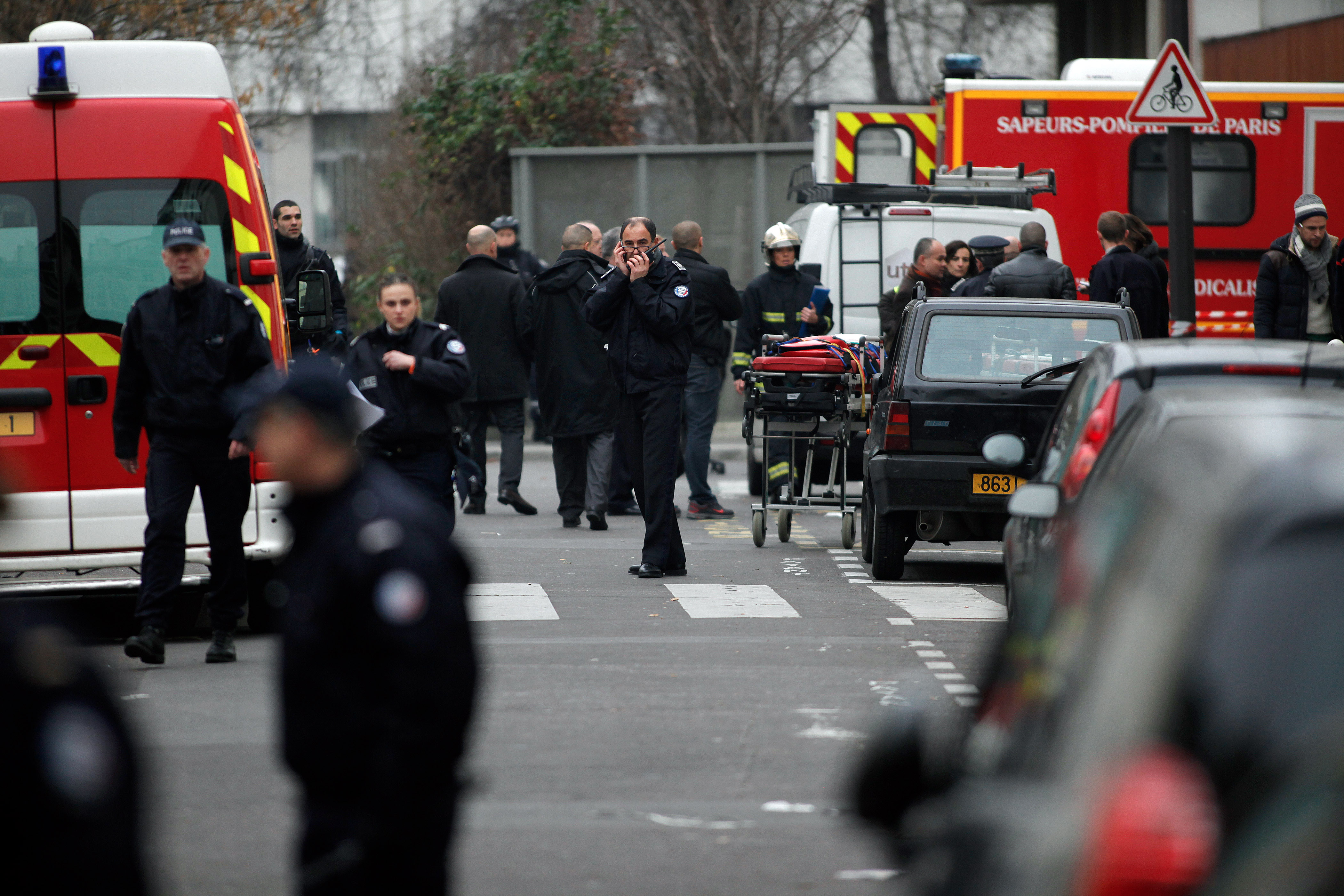 Police officers and firemen gather  outside the French satirical newspaper Charlie Hebdo's office, in Paris, Wednesday, Jan. 7, 2015. Masked gunmen stormed the offices of a French satirical newspaper Wednesday, killing at least 11 people before escaping, police and a witness said. The weekly has previously drawn condemnation from Muslims.  (AP Photo/Thibault Camus) (AP)