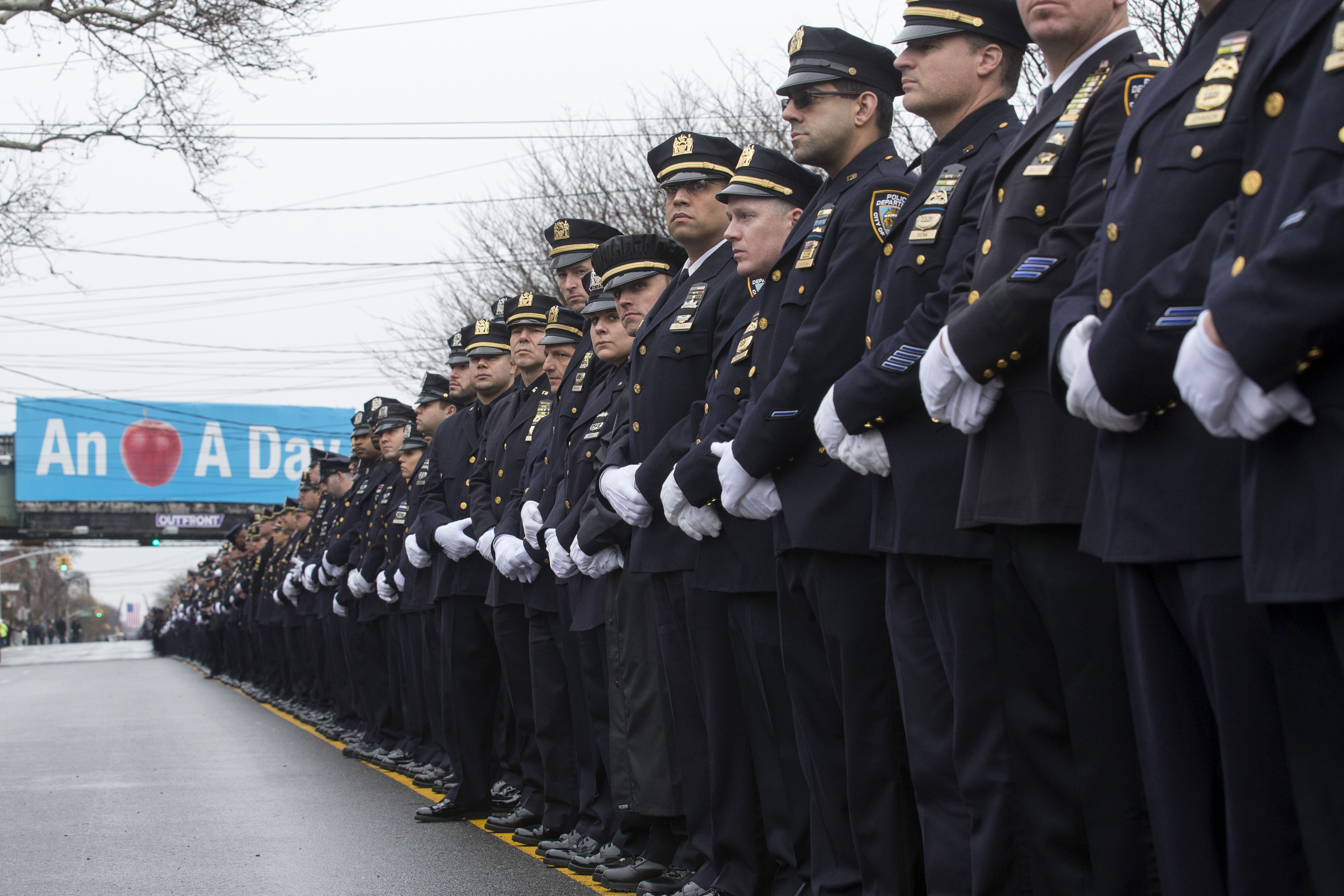 Police officers stand along the procession route during the funeral of New York Police Department Officer Wenjian Liu, Sunday, Jan. 4, 2015, in the Brooklyn borough of New York. Liu and his partner, officer Rafael Ramos, were killed Dec. 20 as they sat in their patrol car on a Brooklyn street. The shooter, Ismaaiyl Brinsley, later killed himself. (AP/John Minchillo)