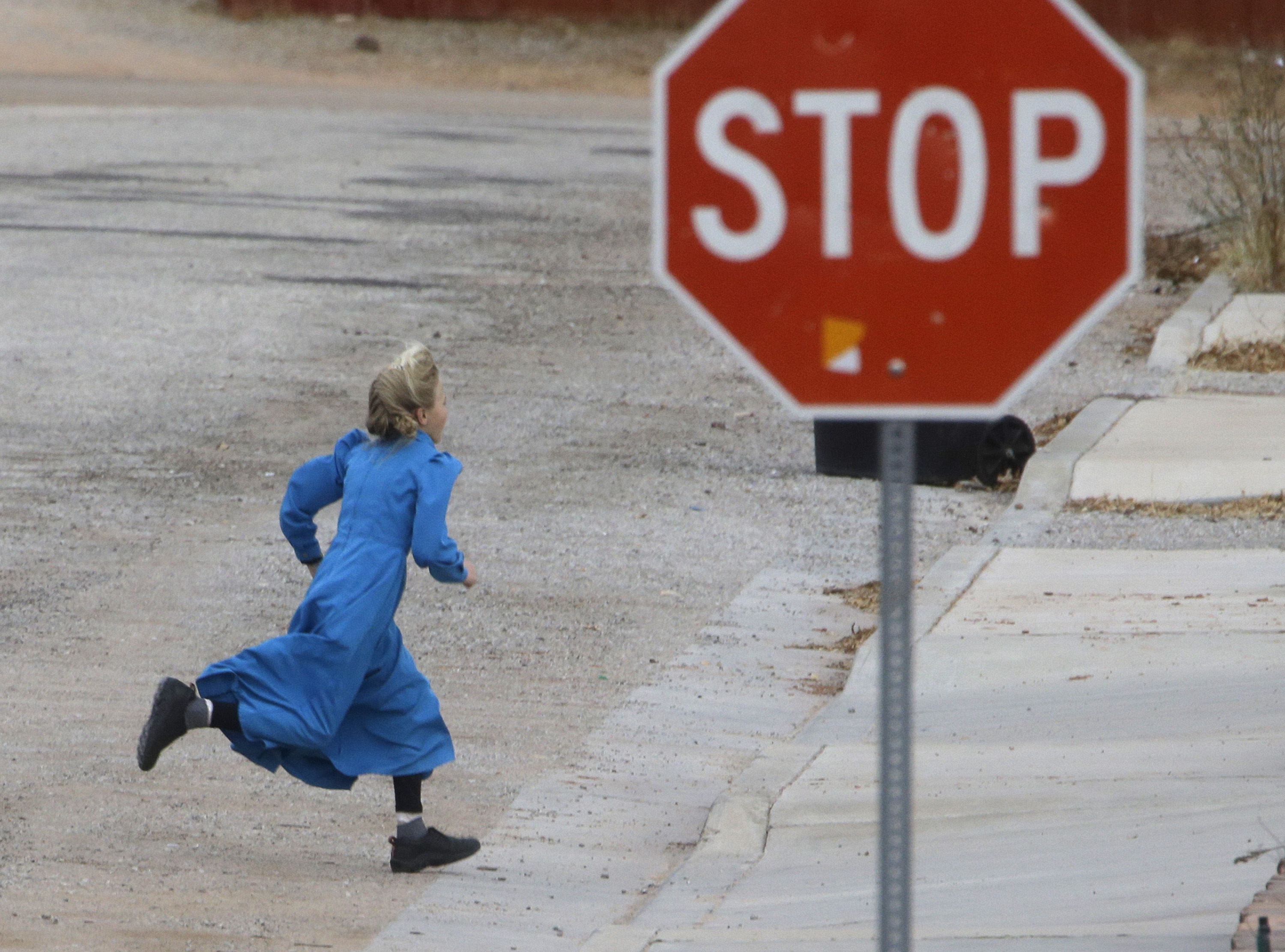 In this Dec. 16, 2014 photo, a girl runs past a street sign in Hildale, Utah. The sister cities of Hildale and Colorado City, Ariz., once run by polygamist leader Warren Jeffs, are split between loyalists who still believe he is a victim of religious persecution and defectors who are embracing government efforts to pull the town into modern society. (AP Photo/Rick Bowmer) (AP)