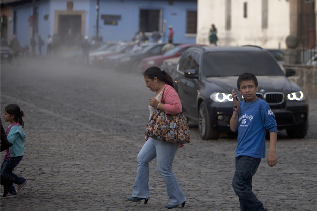 People cross a street covered with ash from the eruption of the Fuego Volcano at Antigua Guatemala, Saturday, Feb. 7, 2015. (AP/Moises Castillo)