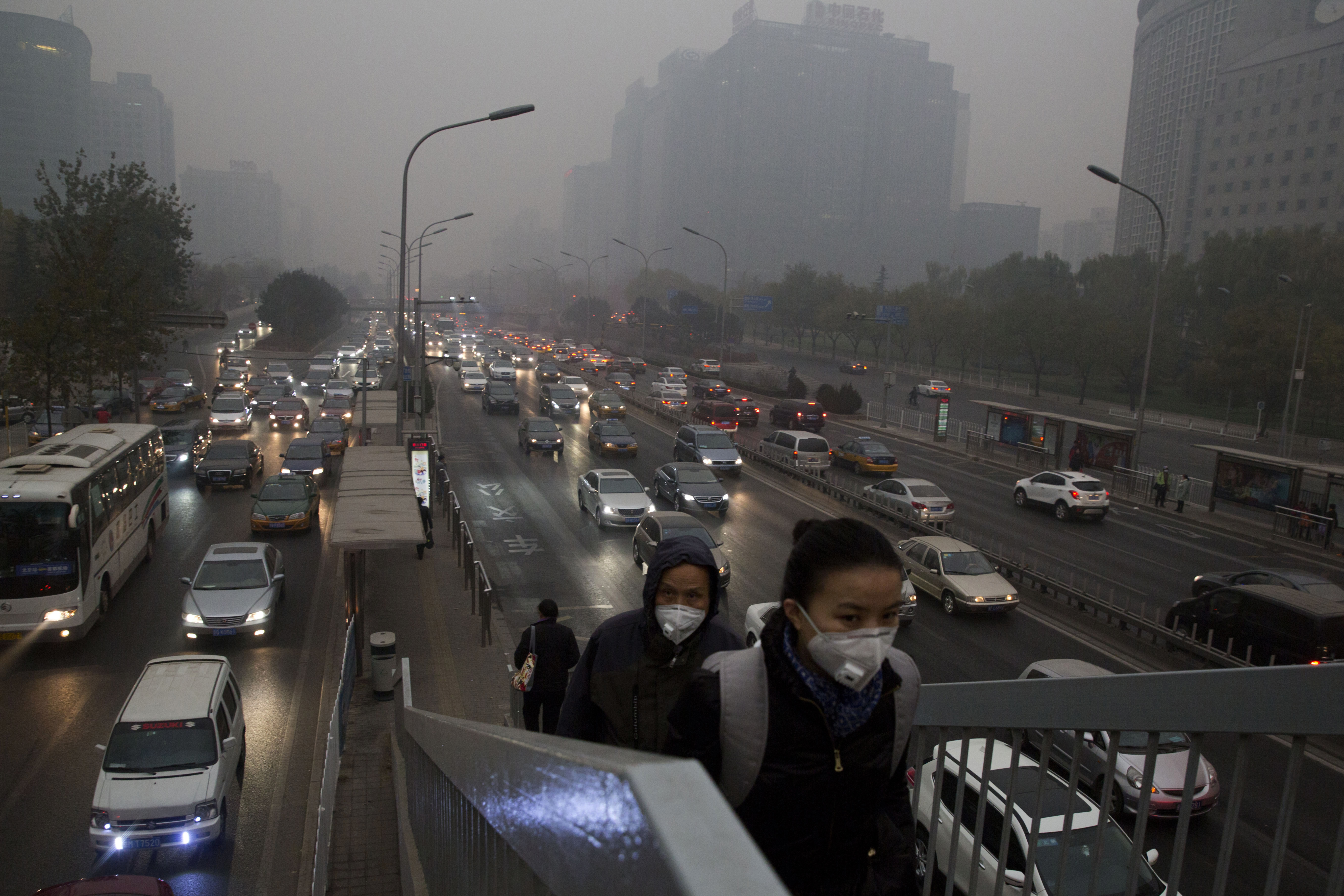 FILE - In this file photo taken Saturday, Nov. 29, 2014, pedestrians wear masks against the pollution as they cross an overhead bridge over a busy highway in Beijing, China. A slick new documentary on China's environmental woes has racked up more than 175 million online views in two days, underscoring growing concern in the country over the impact of air, water and soil pollution. Costing about $160,000 to make, the documentary won praise Sunday March 1, 2015, from new Chinese Environment Minister Chen Jining. (AP Photo/Ng Han Guan, File) (AP)