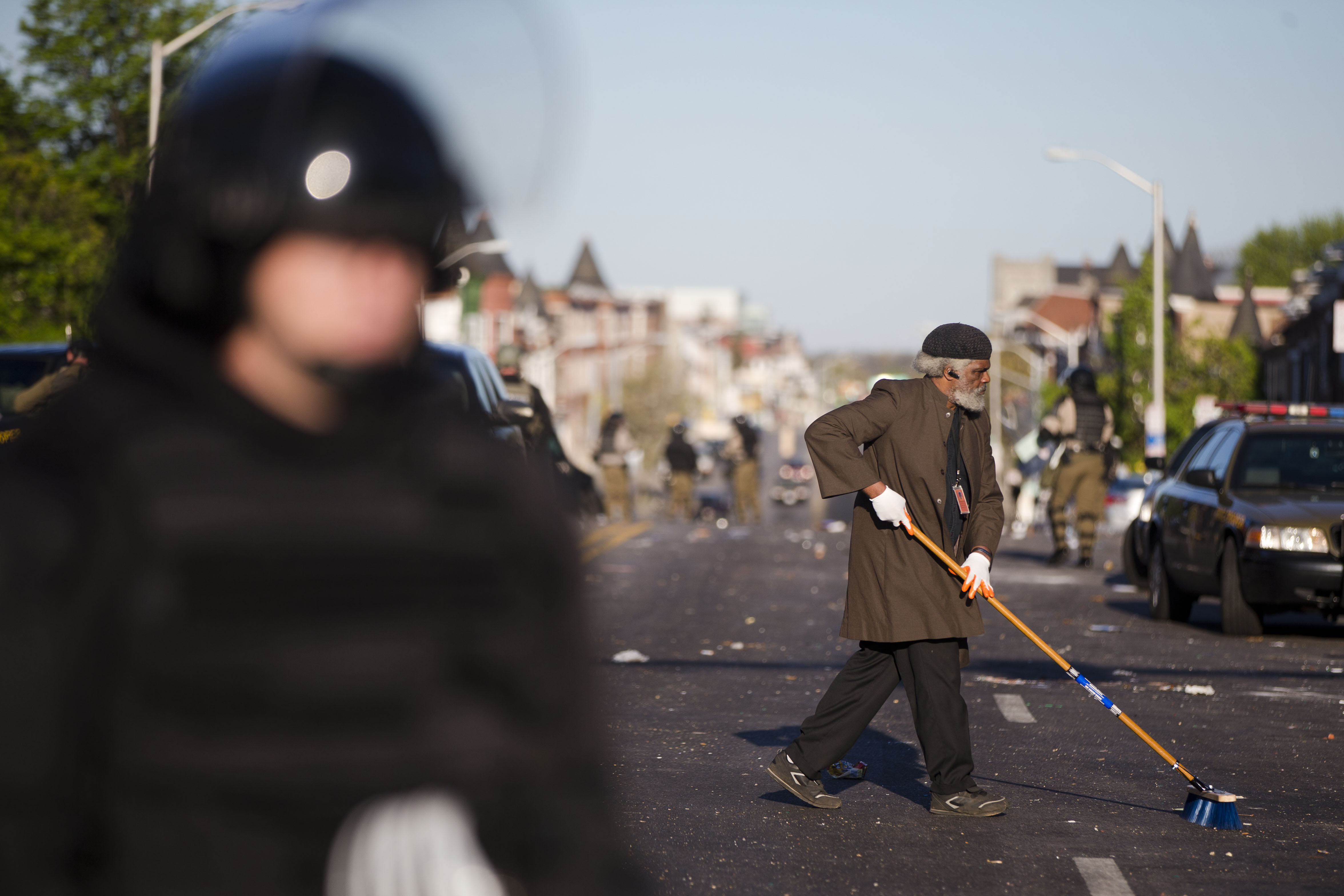 Residents clean streets as law enforcement officers stand guard, Tuesday, April 28, 2015, in Baltimore, in the aftermath of rioting following Monday's funeral of Freddie Gray, who died in police custody. (AP Photo/Matt Rourke) (AP)