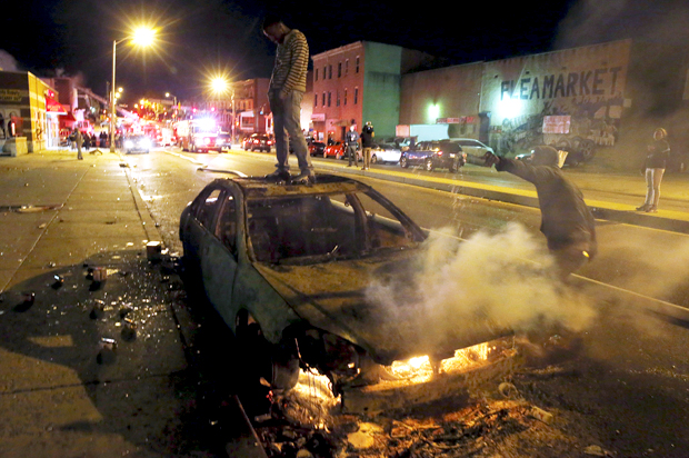 A rioter stands atop a burning car in Baltimore, Maryland April 27, 2015. (Reuters/Jim Bourg)