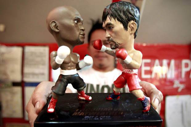A store employee holds up miniature figurines of Manny Pacquiao and Floyd Mayweather Jr., Manila, April 23, 2015. (Reuters/Romeo Ranoco)