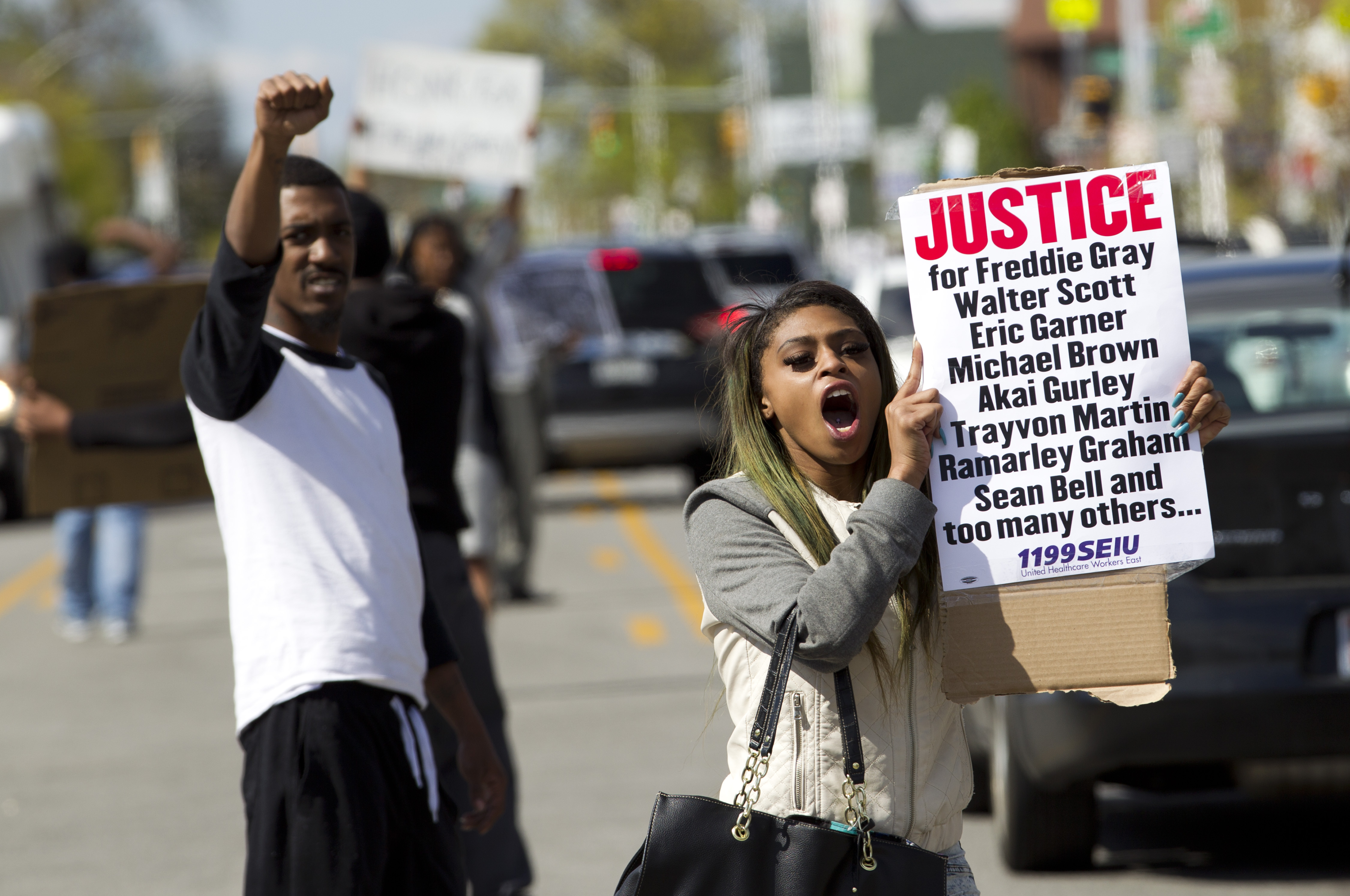 Caira Byrd hold support signs for Freddie Gray outside of Vaughn Greene Funeral Home, during his wake in Baltimore, Md., Sunday, April 26, 2015. Gray died from spinal injuries about a week after he was arrested and transported in a police van. (AP/Jose Luis Magana)