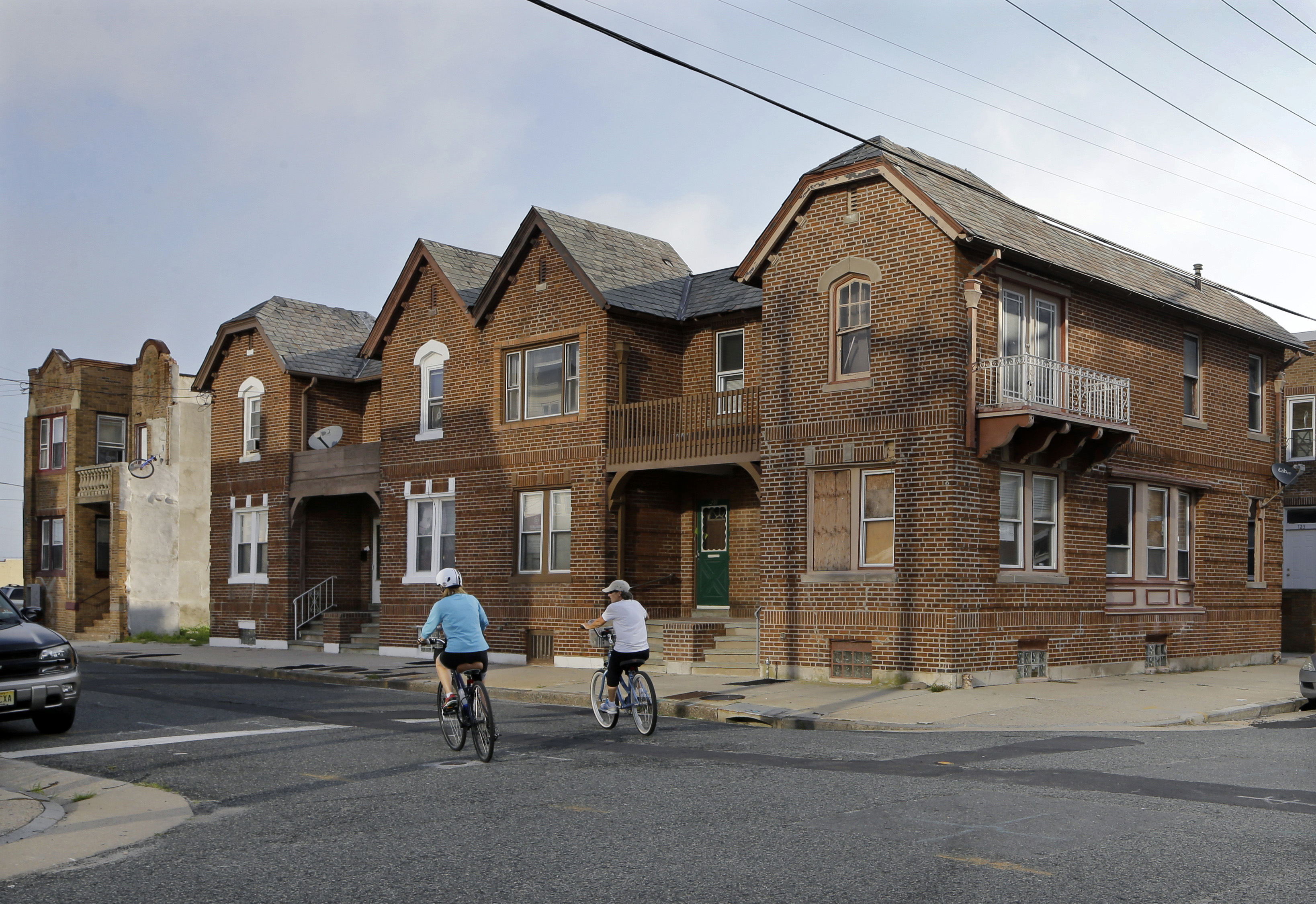 FILE  In this Wednesday, July 23, 2014 file photograph, a pair of bicyclists pedal past older attached homes, some with boarded windows on the north end of Atlantic City, N.J. A loan program that was supposed to lend as much as $40 million to struggling homeowners and businesses in this cash-strapped resort city has given out nothing and instead led to a federal lawsuit. Atlantic City is suing to get back $3 million it gave to the company that has failed to run the Community Loan Program, launched in 2013 by Lorenzo Langford, the mayor at the time. (AP Photo/Mel Evans,file)
