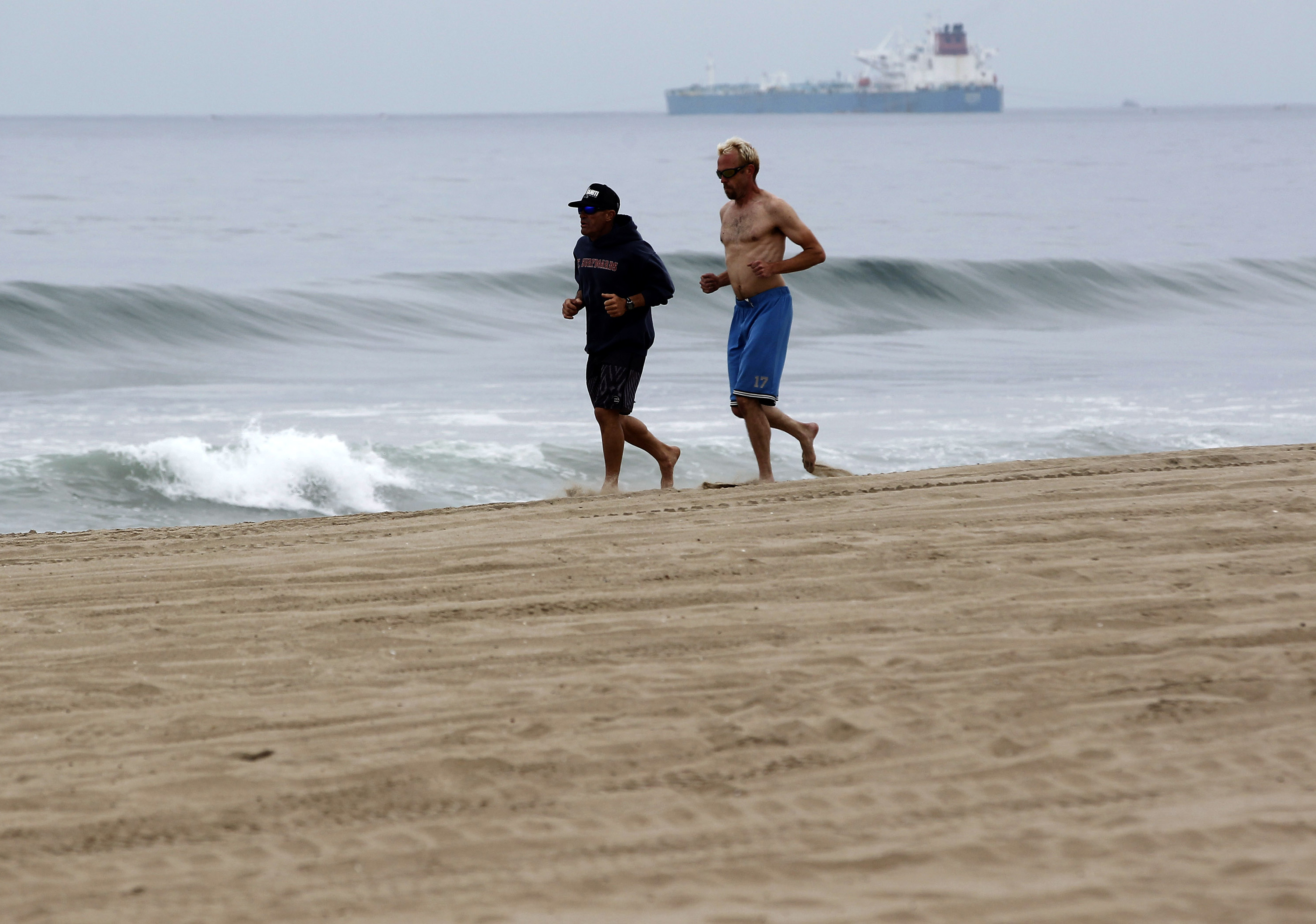 Morning joggers make their way along the beach in Manhattan Beach, Calif. on Thursday, May 28, 2015. Popular beaches along nearly 7 miles of Los Angeles-area coastline are off-limits to surfing and swimming after balls of tar washed ashore. The beaches along south Santa Monica Bay appeared virtually free of oil Thursday morning after an overnight cleanup, but officials aren't sure if more tar will show up. (AP Photo/Nick Ut) (AP)