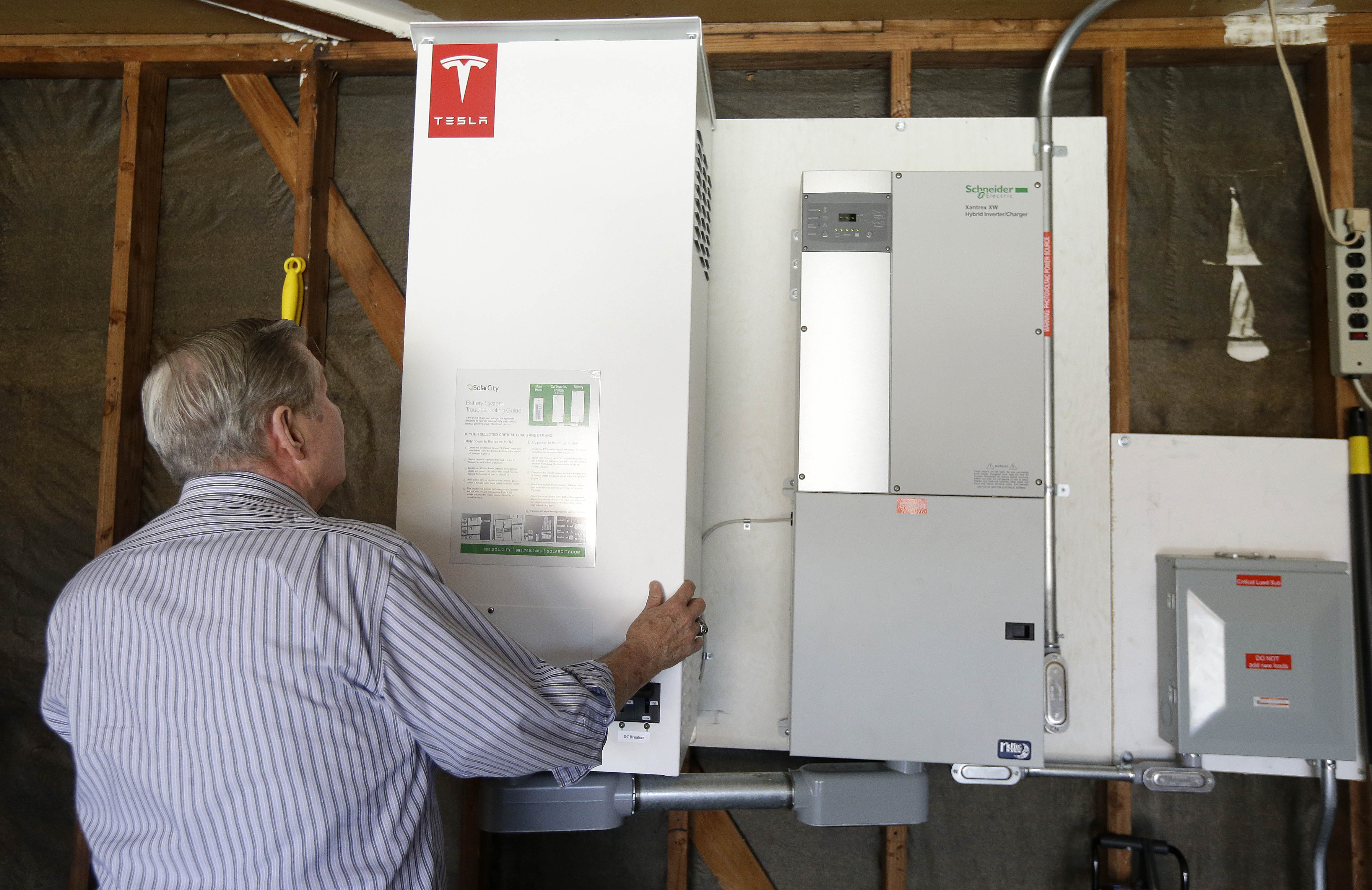 In this April 20, 2015 photo, David Cunnigham shows a prototype Tesla battery system that powers his Foster City, Calif. home. (AP Photo/Jeff Chiu)