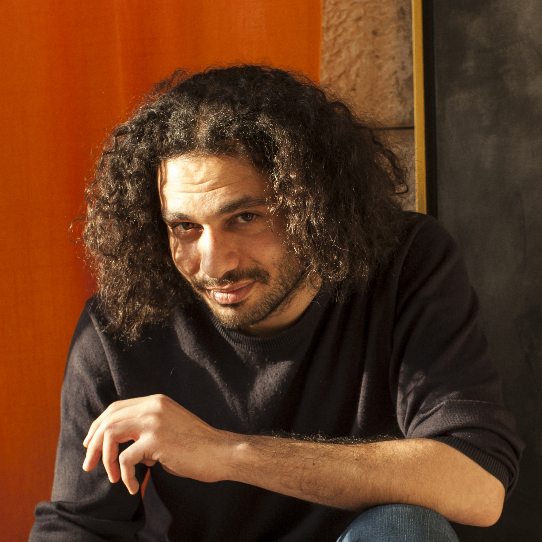 Amer Shomali in his art studio in Ramallah, in front of his painting, a character in the film "The Wanted 18". (Tanya Habjouqa)