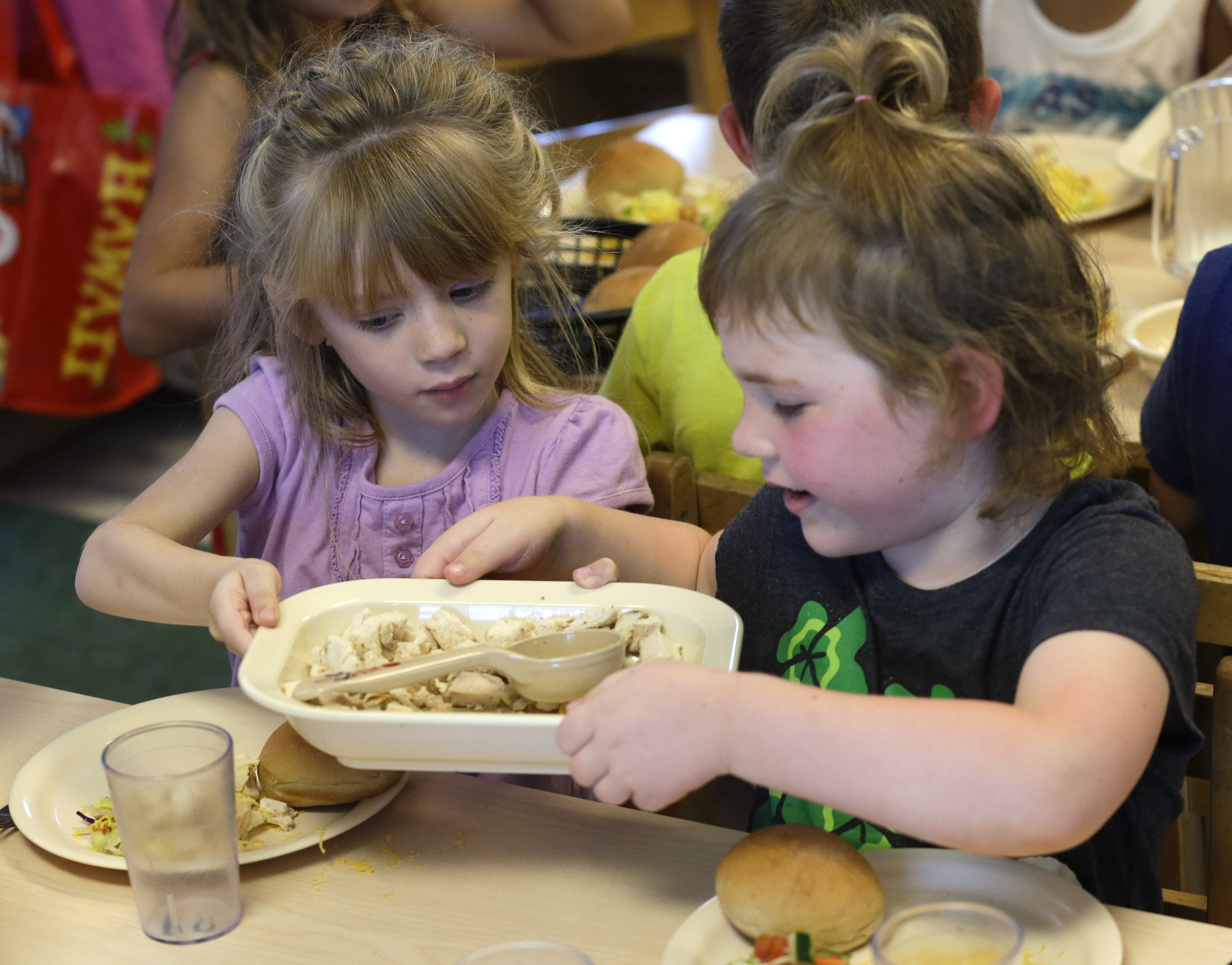 Rebekah Webb, left, shares a family-style meal with Zoe Turner during lunch with other five-year-olds at the Olathe Family YMCA in Olathe, Kan., Wednesday, June 24, 2015. As early childhood teachers lament toddlers too large to fit in playground swings, officials are mulling changes designed to make meals served to millions of kids in day care healthier.  (AP Photo/Orlin Wagner) (AP)