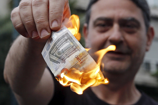 Anti-austerity protesters burn a euro note during a demonstration outside the European Union (EU) offices in Athens, Greece June 28, 2015. (Reuters/Alkis Konstantinidis)