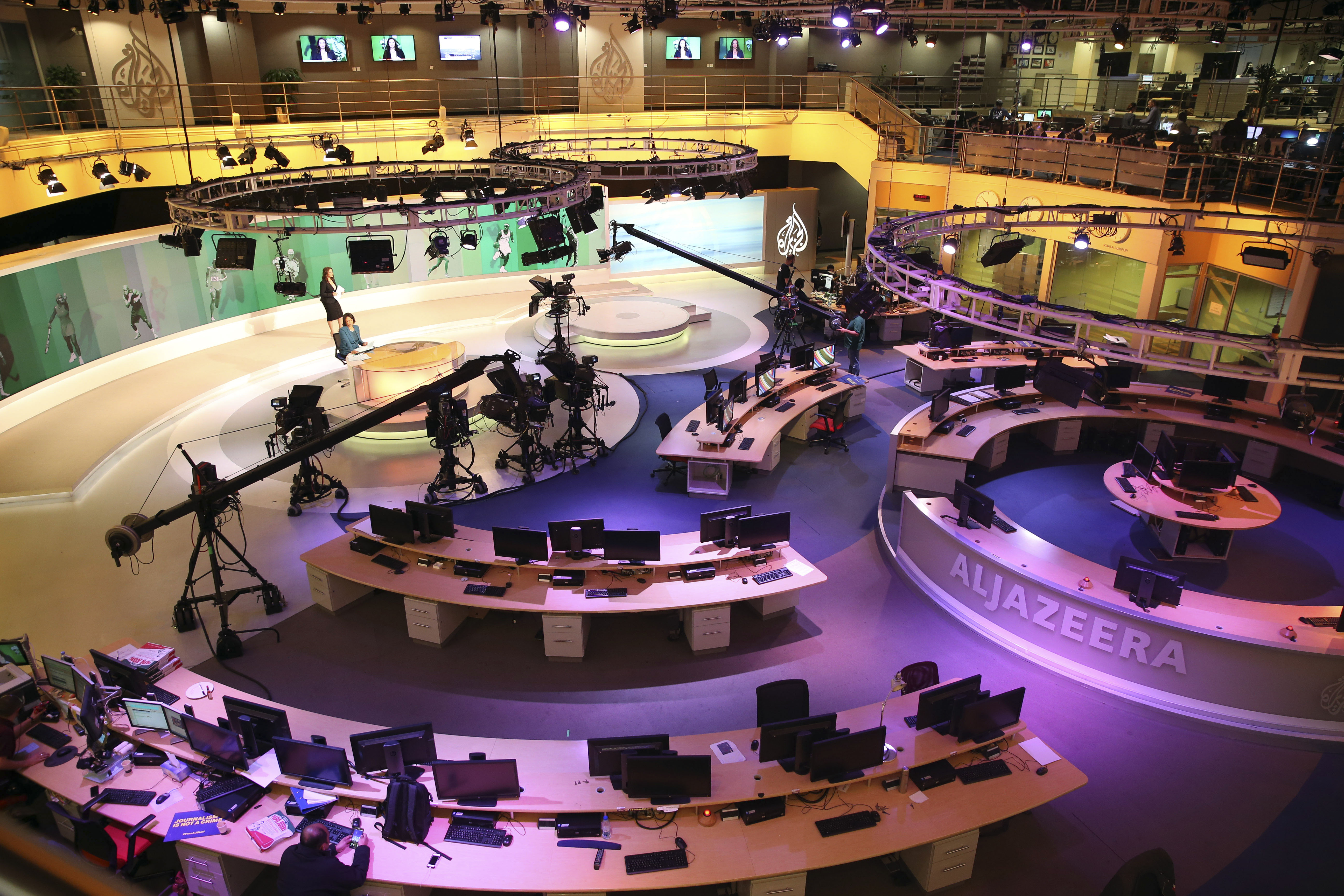 FILE- In this Jan. 1, 2015, file photo, staff members of Al-Jazeera International work at the news studio in Doha, Qatar. (AP Photo/Osama Faisal, File)