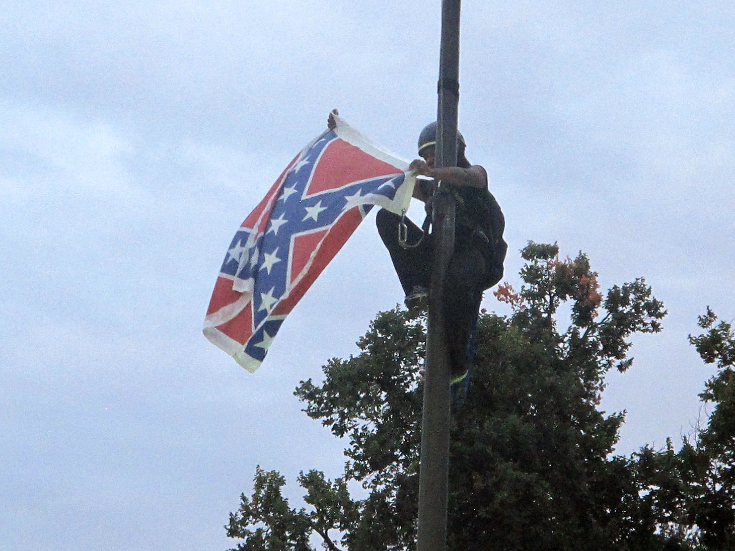 Bree Newsome of Charlotte, N.C., removes the Confederate battle flag at a Confederate monument at the Statehouse in Columbia, S.C. She was taken into custody when she came down. The flag was raised again by capitol workers about 45 minutes later. (AP Photo/Bruce Smith)