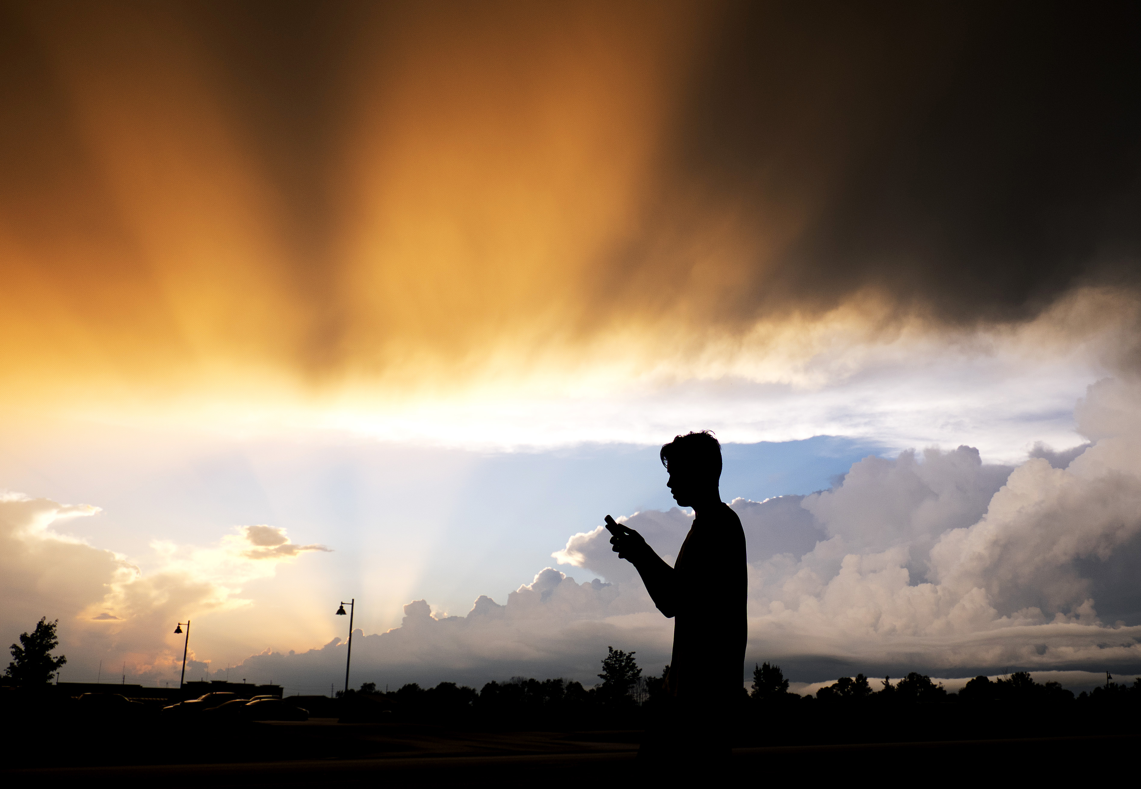 AP10ThingsToSee - A teenager checks his cell phone as storm clouds pass Friday, July 17, 2015, in Zionsville, Ind. Scattered storms were in the forecast for most of Friday evening. (AP Photo/Darron Cummings) (AP)
