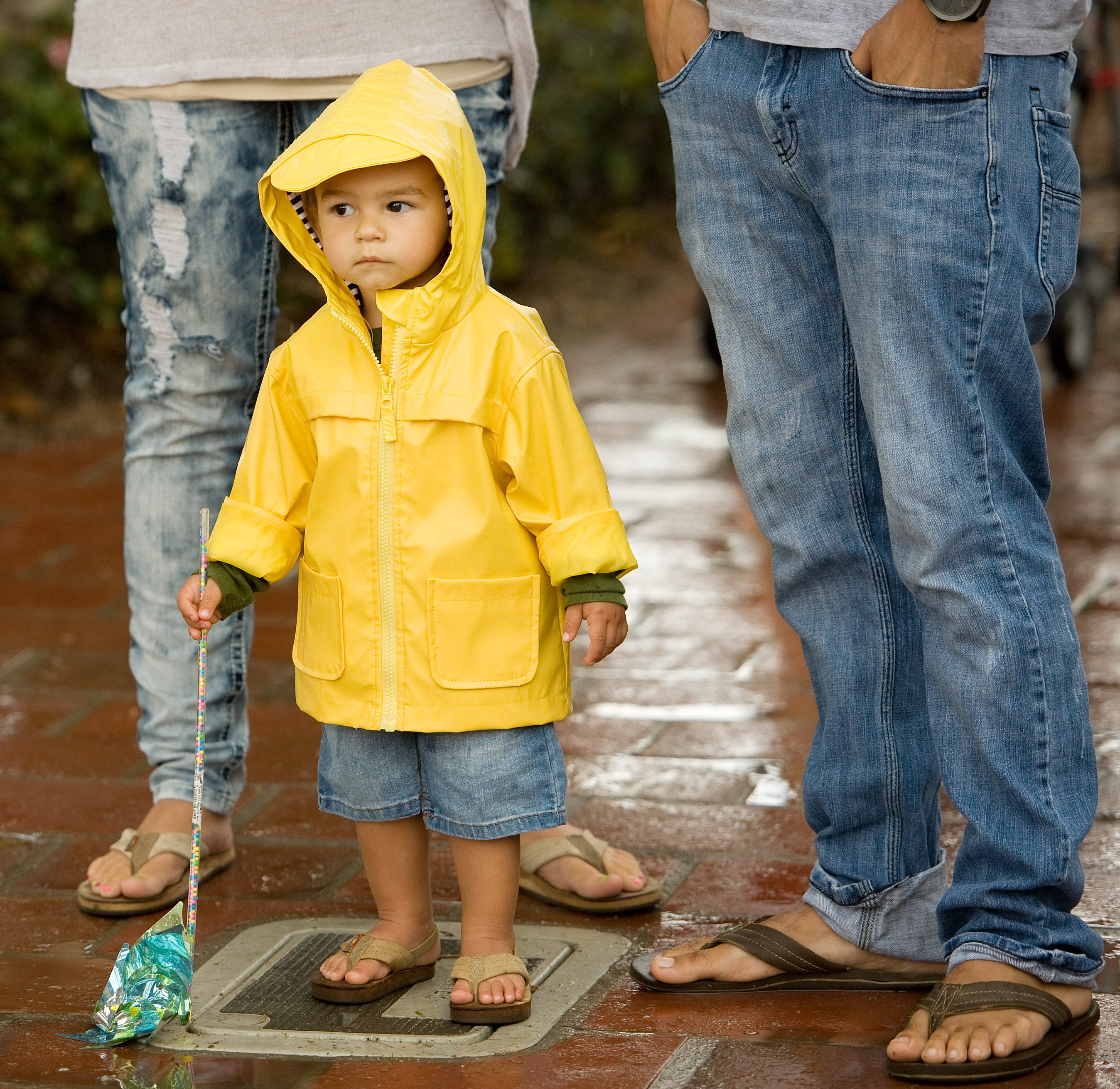 Ezekiel Ekinaka, 1, with his parents Aaron and Juliet, wears a raincoat as he experiences rain for the second time in his life, at the San Clemente, Calif. Ocean Festival before the public was urged to evacuate due to lightning on Saturday, July 18, 2015. (Mindy Schauer/The Orange County Register via AP) (AP)