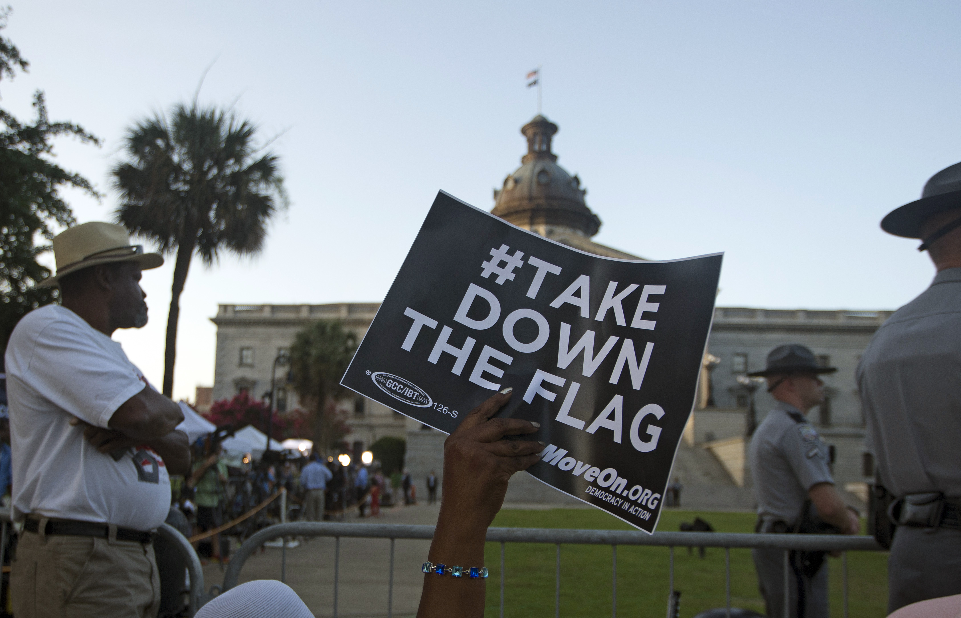 A woman waves a sign as she waits for the Confederate battle flag to be removed from in front of the South Carolina Statehouse, Friday, July 10, 2015, in Columbia, S.C. (AP Photo/John Bazemore)