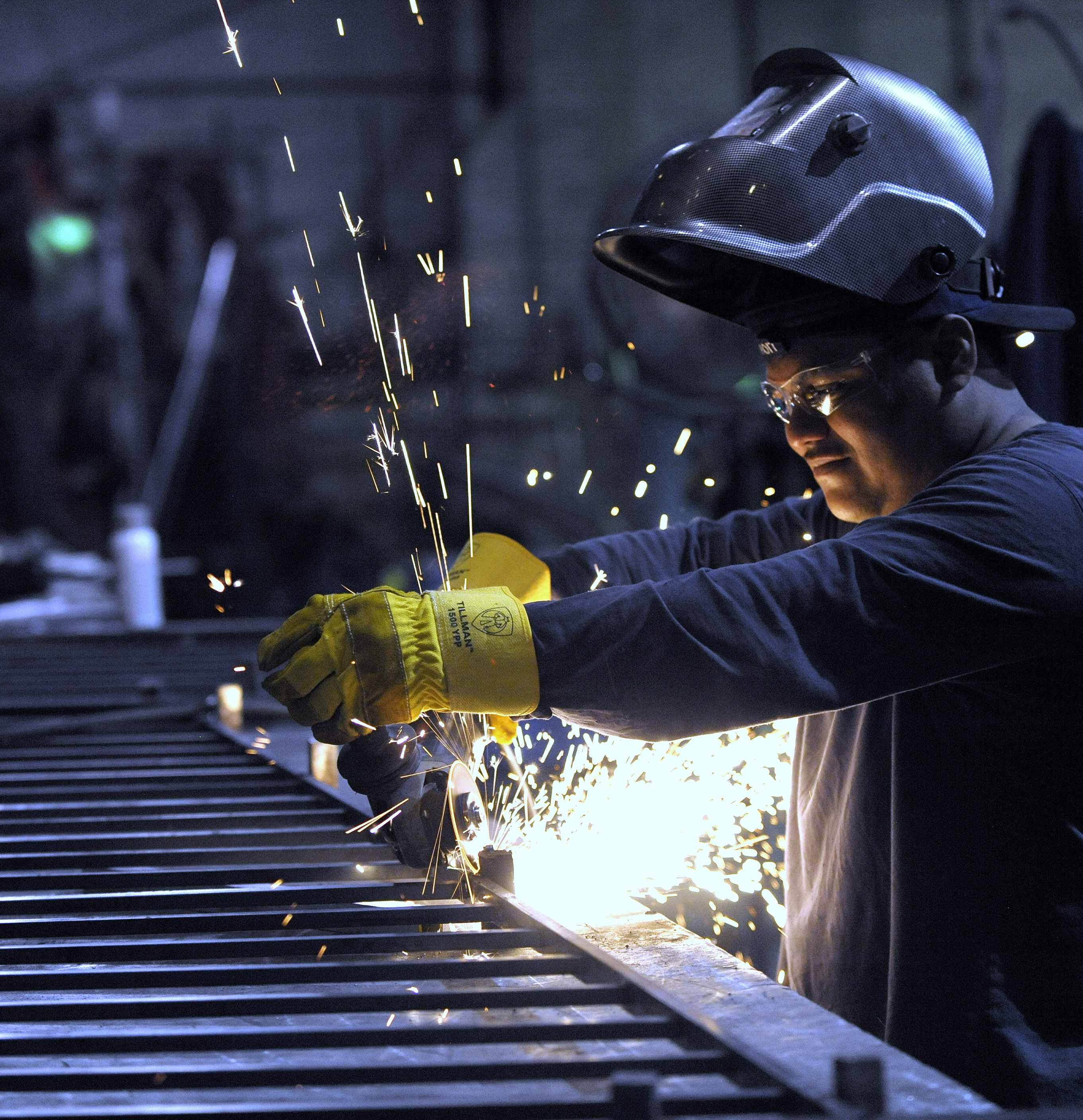 In this photo taken June 11, 2015, a machinist grinds a guardrail for a staircase in Detroit. (Todd McInturf /The Detroit News via AP)